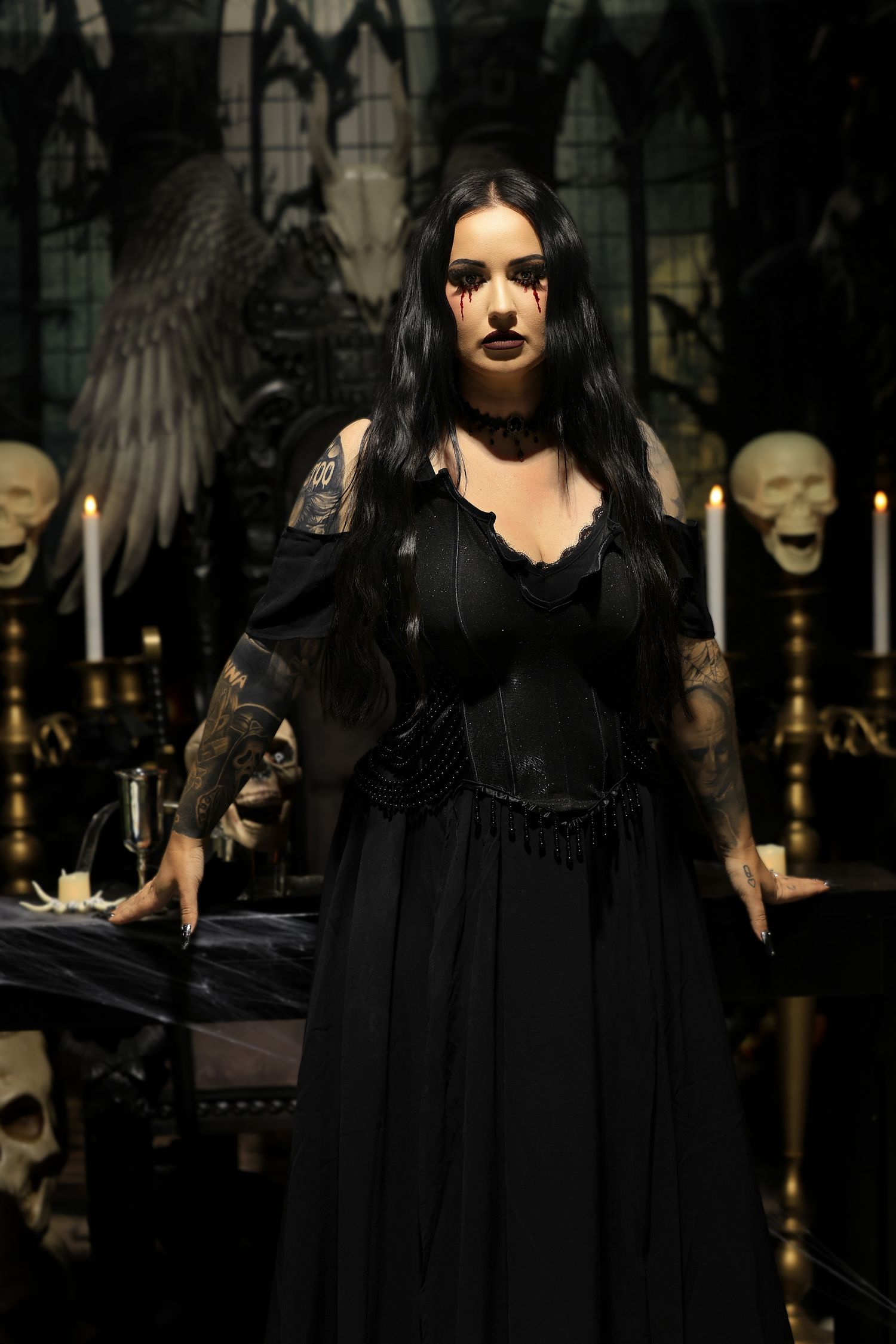 A dark gothic fashion show featuring models in flowing black dresses and dramatic makeup on a dimly lit runway.