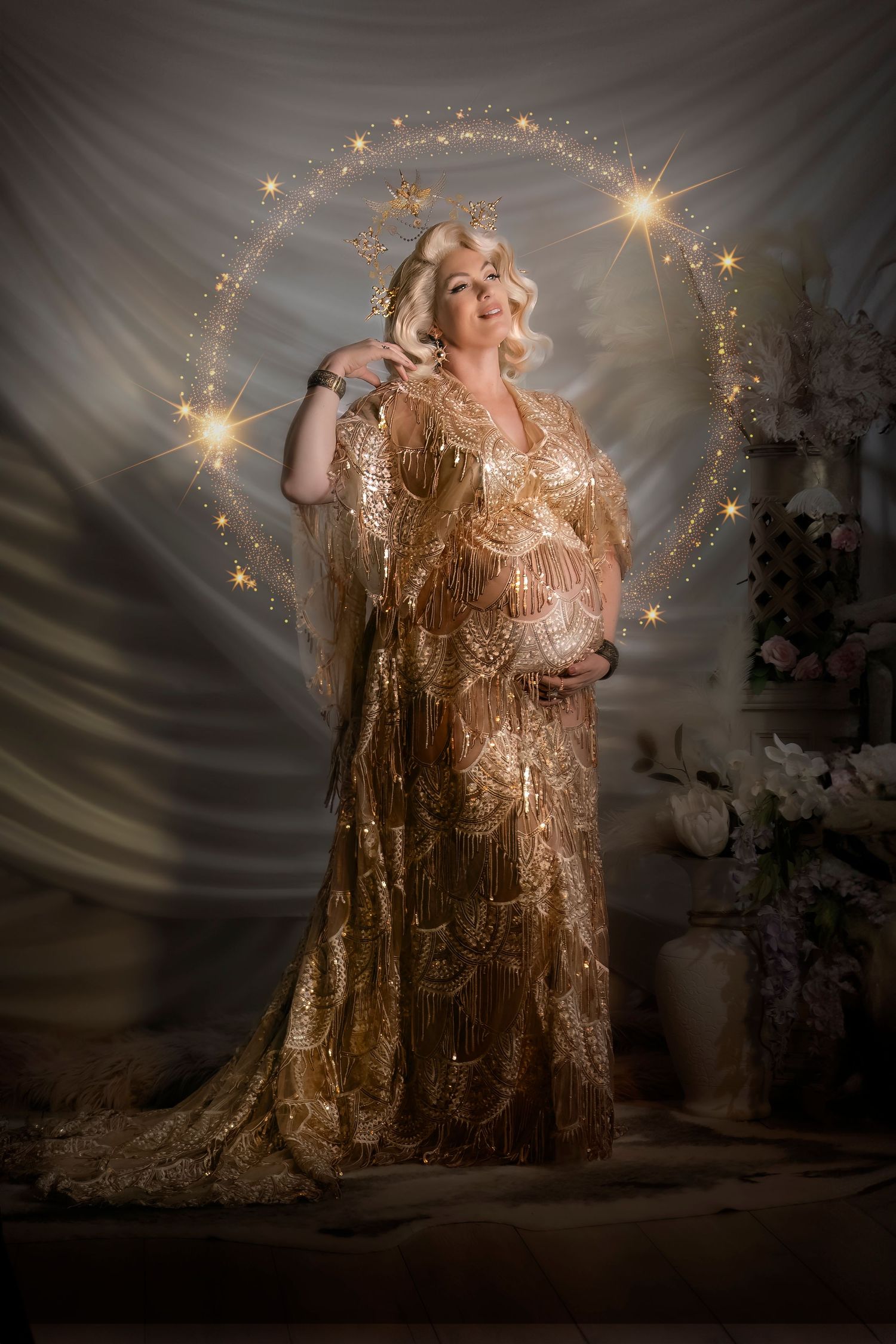 A pregnant figure poses in a glamorous gold sequined gown surrounded by magical twinkling lights and sparkles.