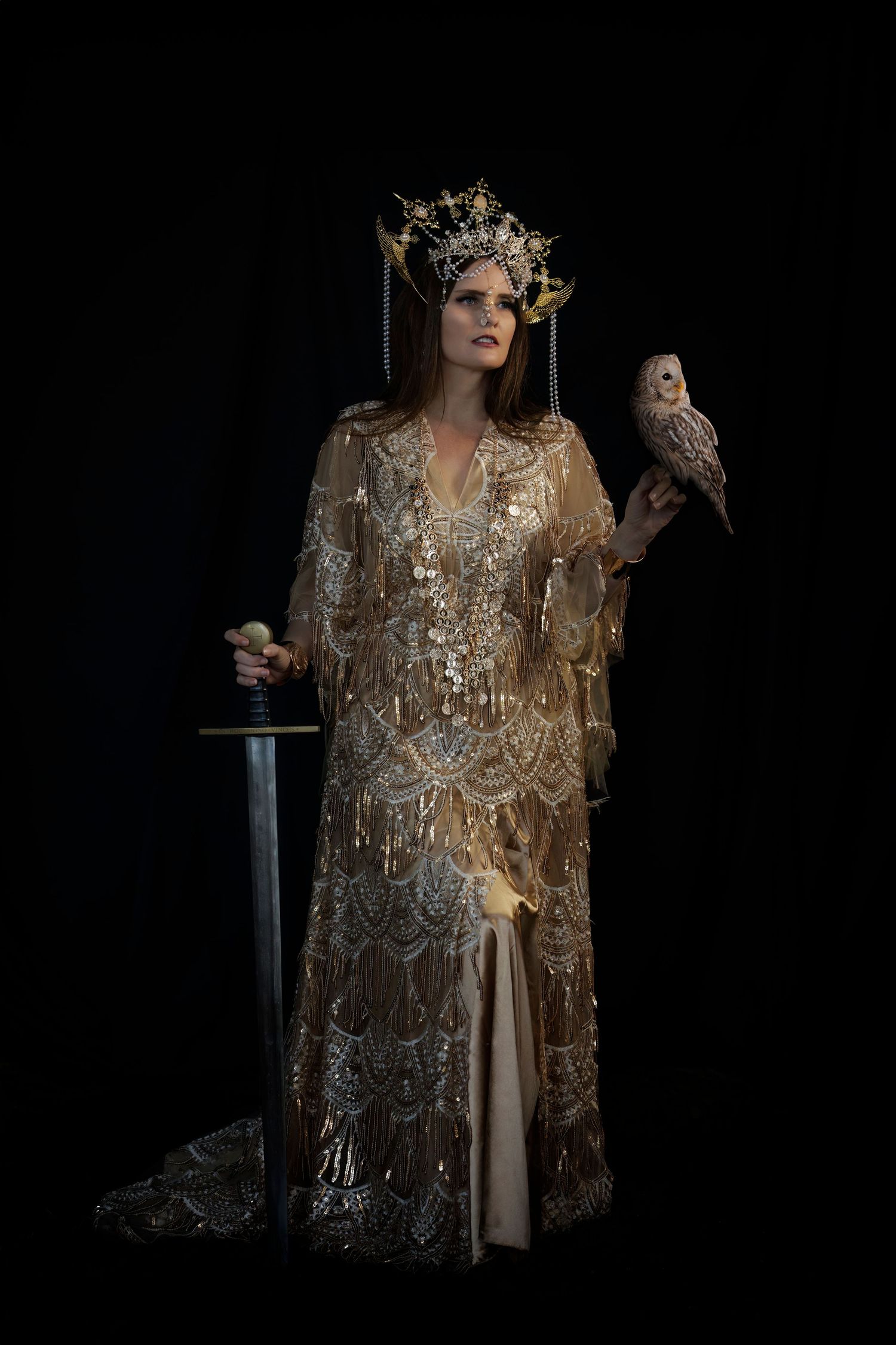 Fantasy portrait with intricate gold dress, ornate crown, and owl companion against dark backdrop.
