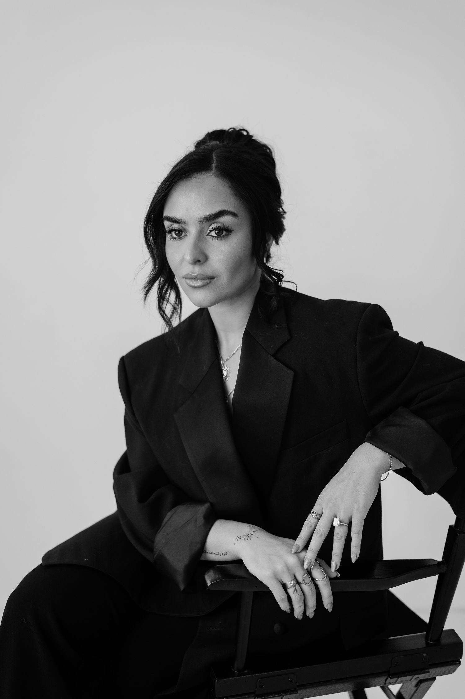 A series of black and white portraits showing someone in a black blazer posing against a white backdrop.