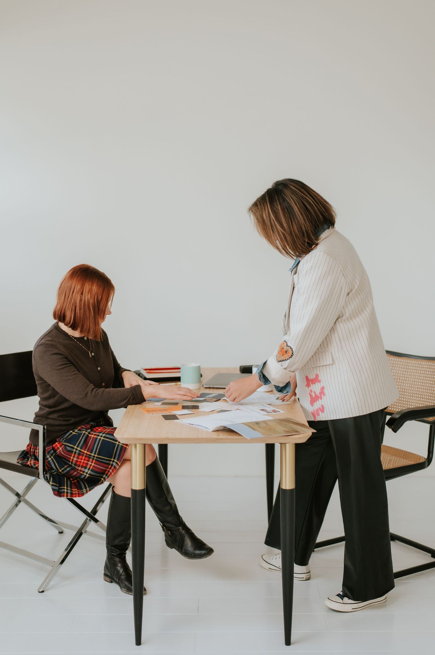 Two people having a business meeting at a modern table with documents and coffee cups spread out on the surface.