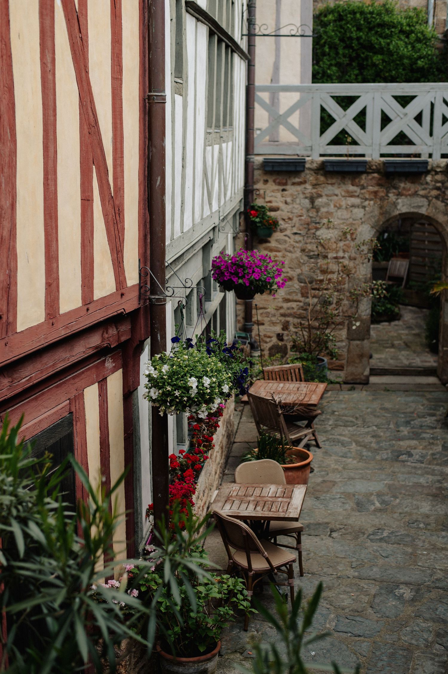 A charming French half-timbered building with colorful flower boxes and outdoor cafe seating on cobblestones.