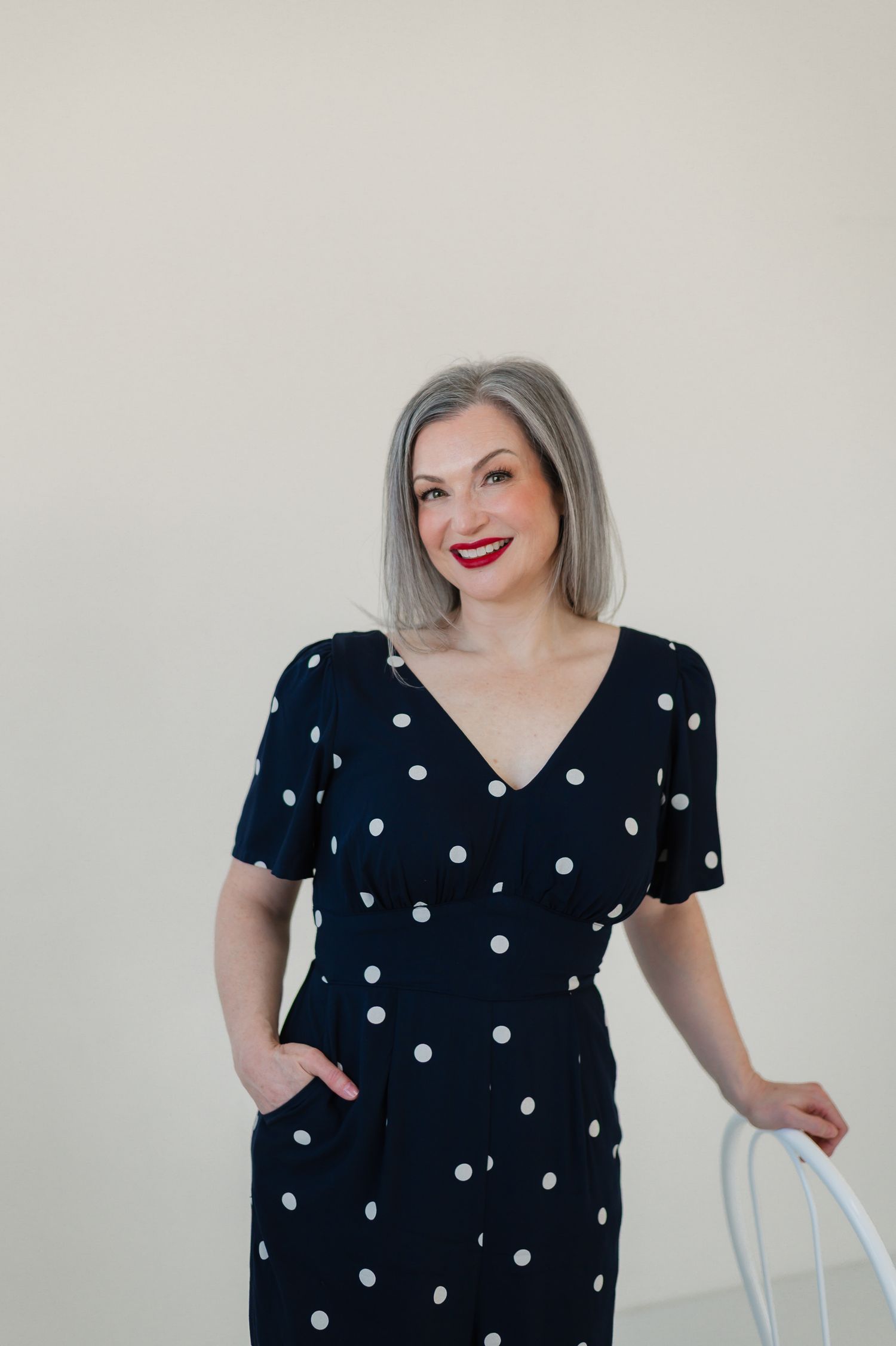 A woman wearing a black and white polka dot dress poses playfully in a series of four connected photos.