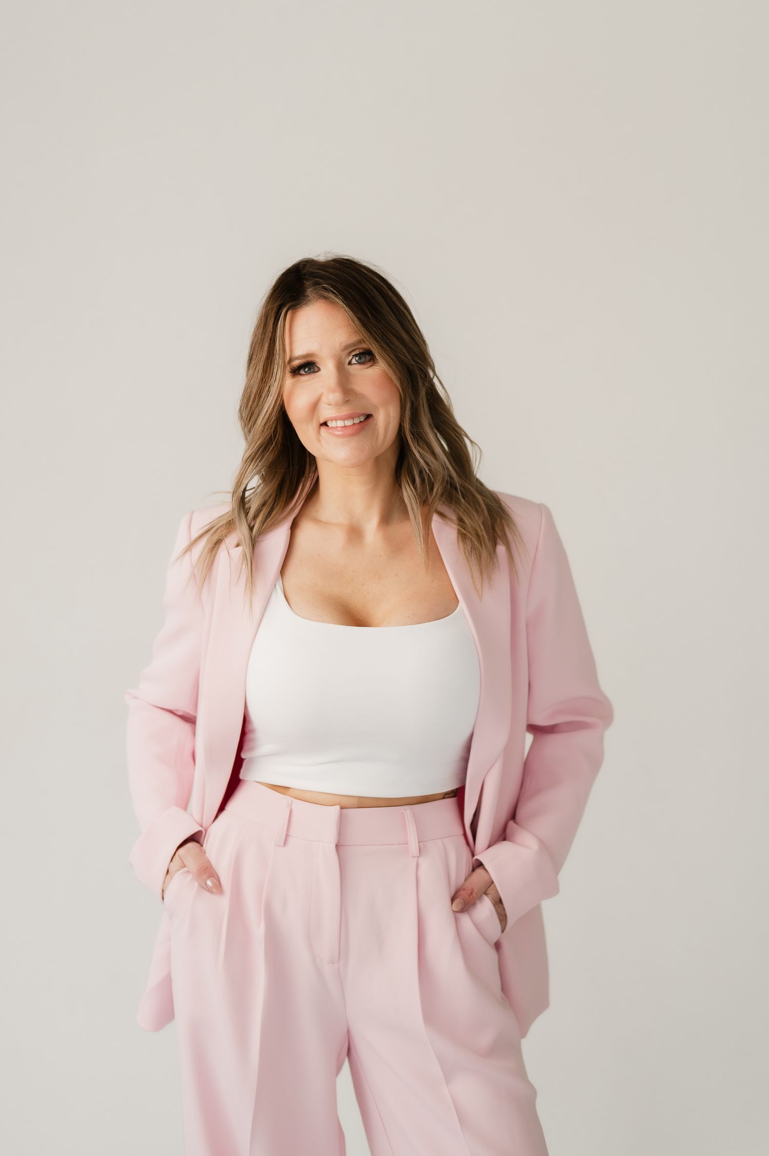 A pink linen blazer and pants set styled with a white crop top in a modern minimalist photoshoot.