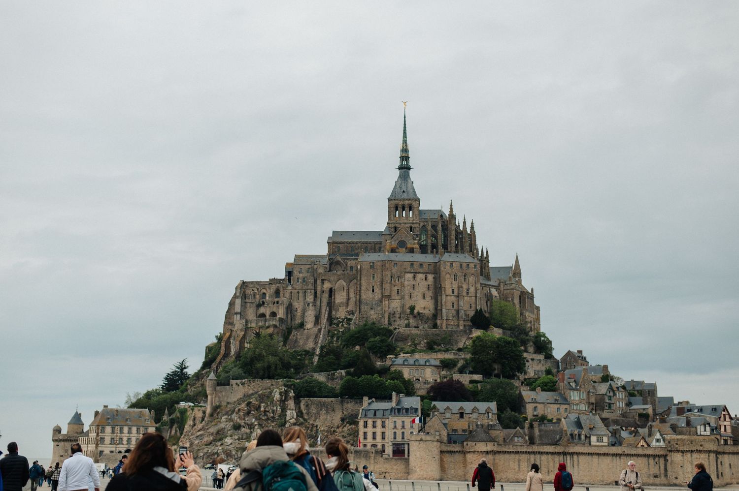 Tourists visiting the iconic Mont Saint-Michel abbey rising dramatically on a rocky island in Normandy, France.
