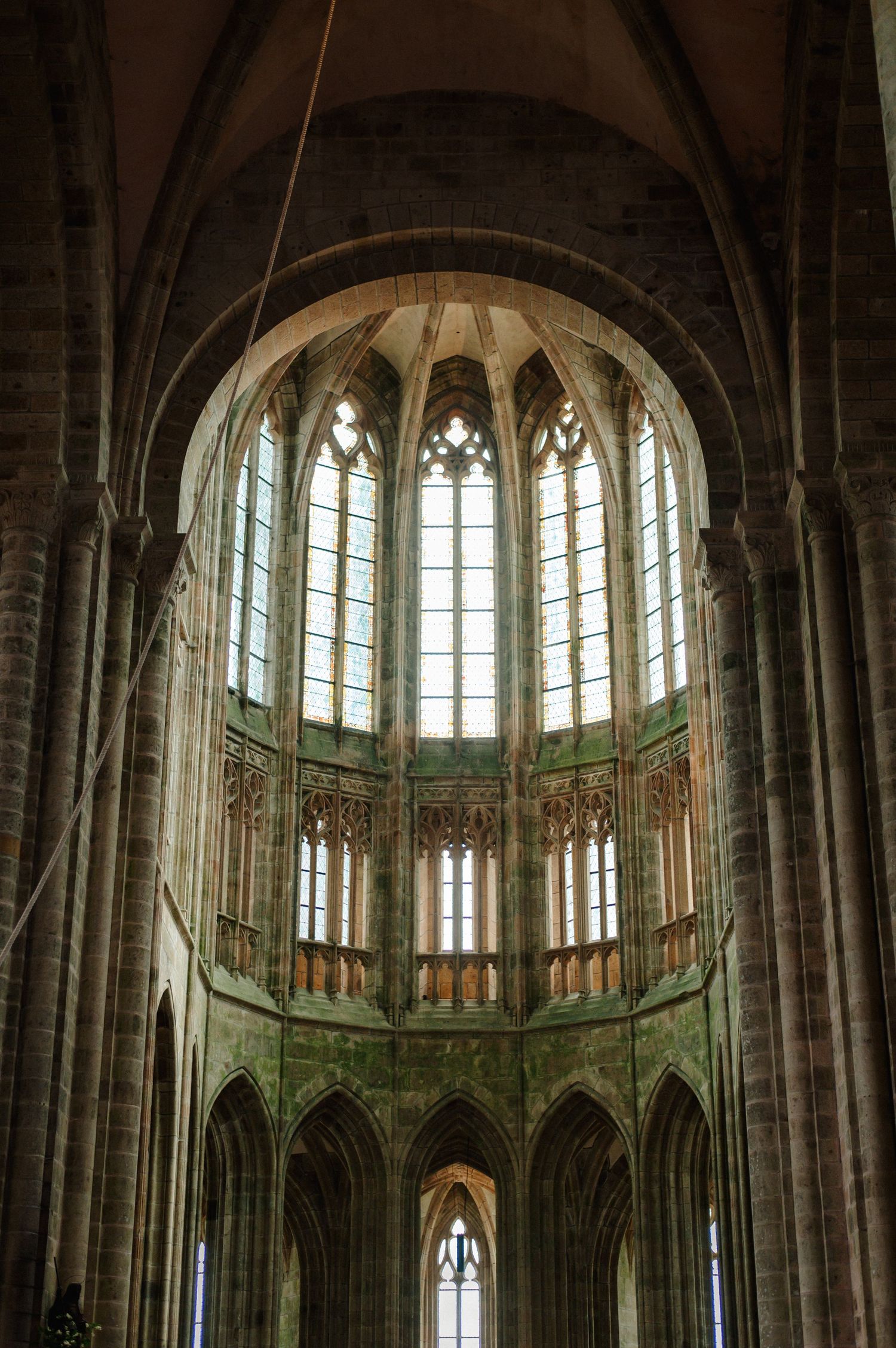 Stunning Gothic interior of Mont Saint-Michel Abbey featuring soaring arched windows and stone vaulted ceilings.