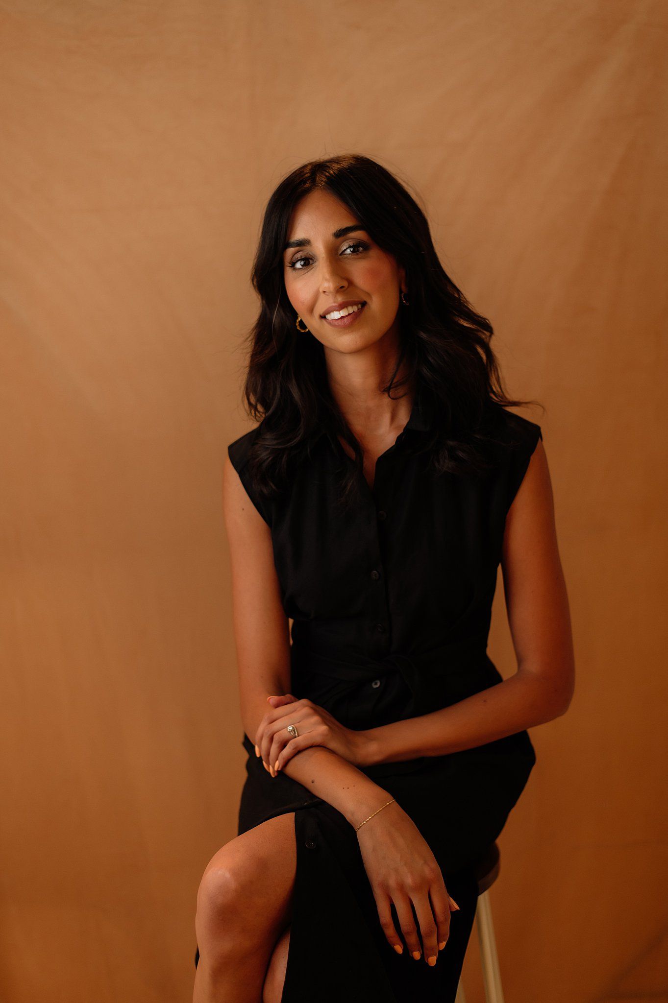 A series of artistic portraits showing someone in a black dress against a warm brown backdrop in different poses.