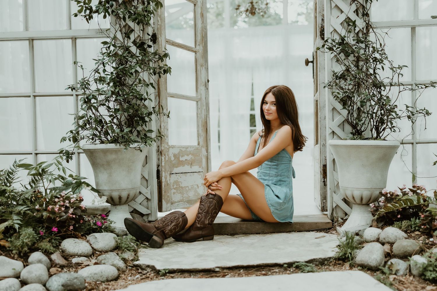 A dreamy photoshoot in a greenhouse with a peacock chair and elegant poses against white curtains.