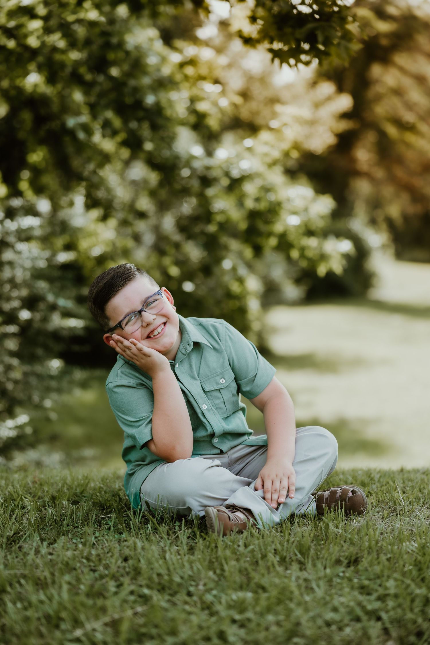 Green-shirted figure reclining on grass during outdoor portrait session.