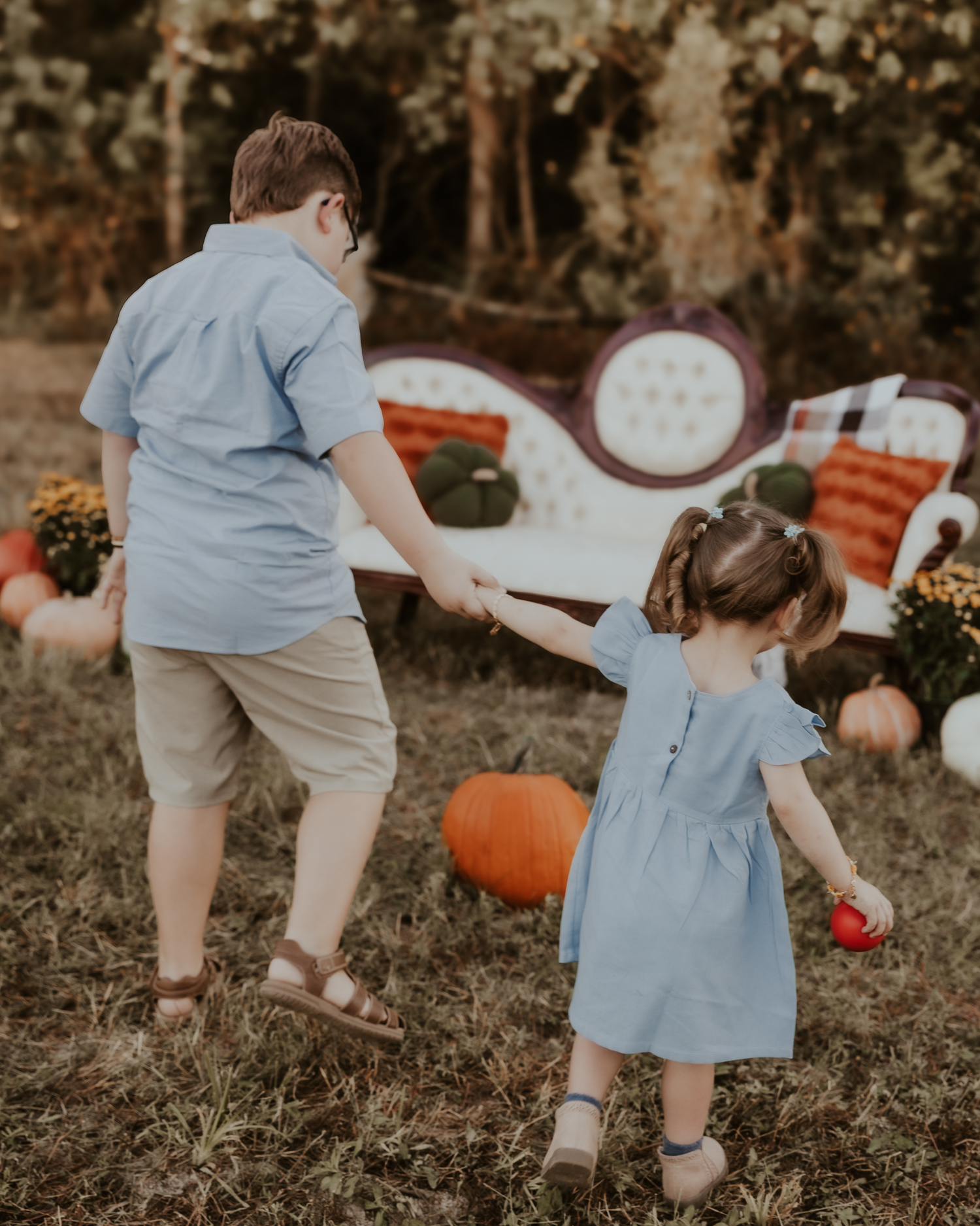 Children playing outdoors in light blue outfits during fall season.