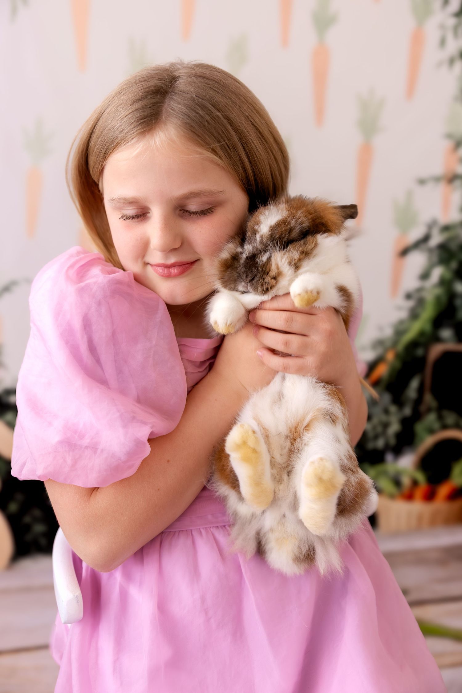 A child in a pink dress hugs a small white and brown rabbit in a series of affectionate poses.