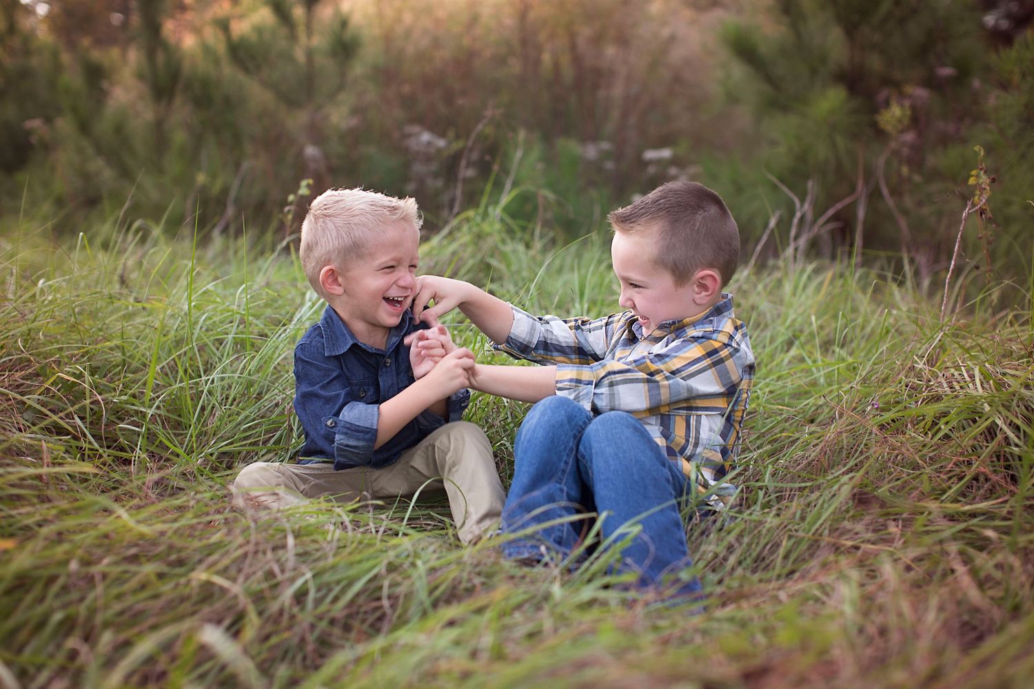 Two children play together in a grassy field during golden hour.
