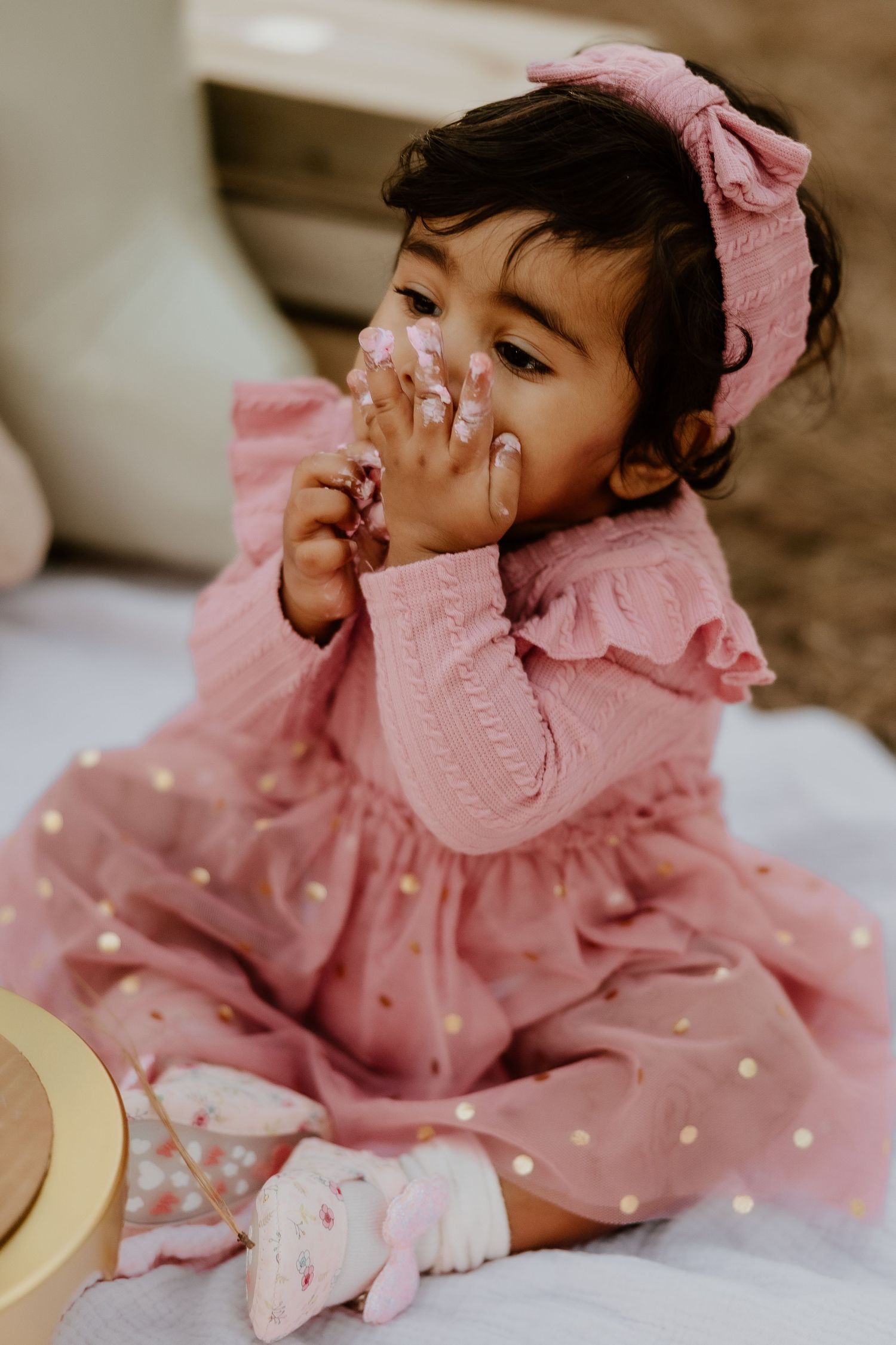 Baby wearing pink polka dot dress with bow lying on floor in series of candid poses.