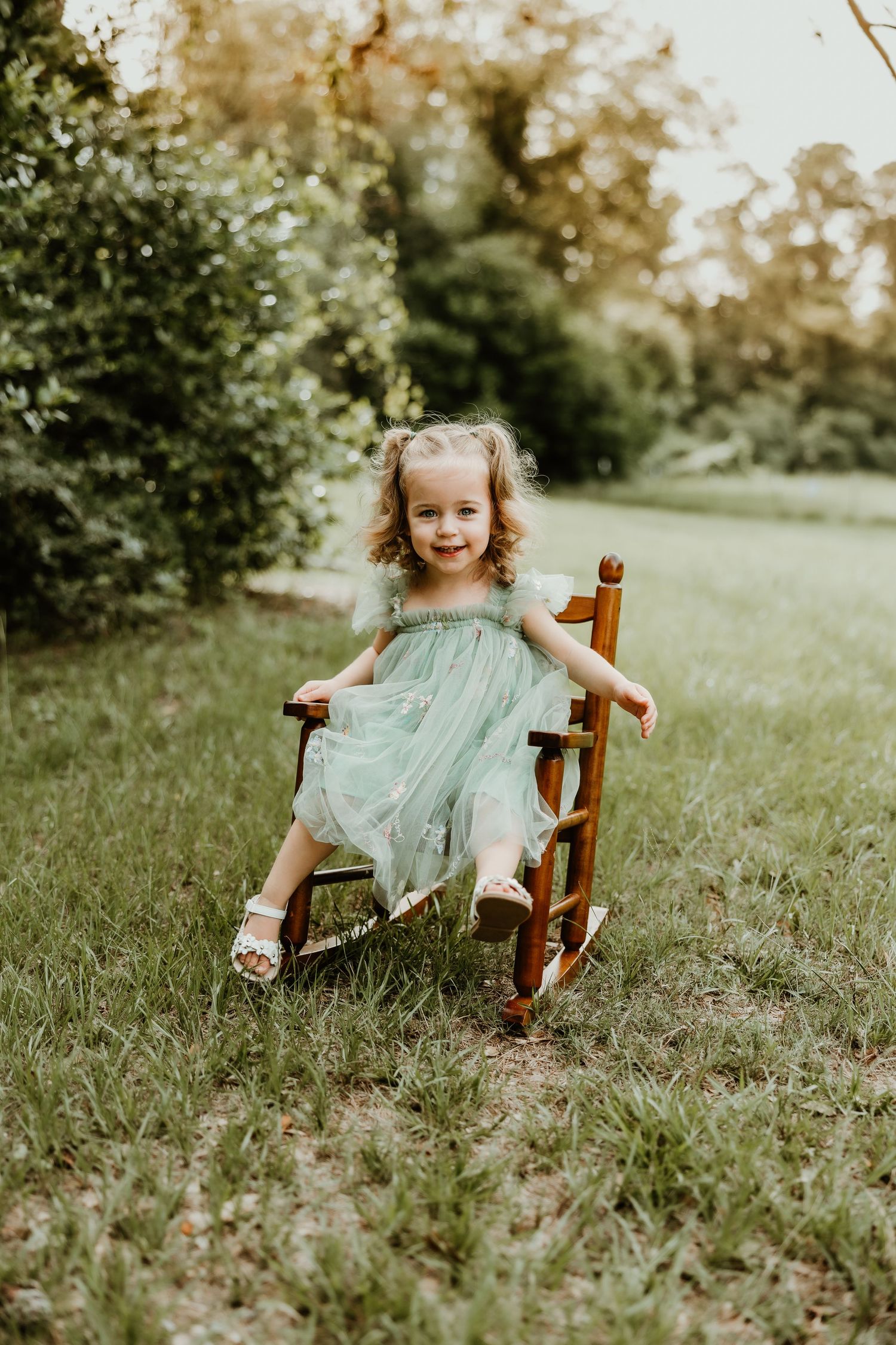 Sweet outdoor photoshoot with a wooden chair in a grassy meadow during golden hour.