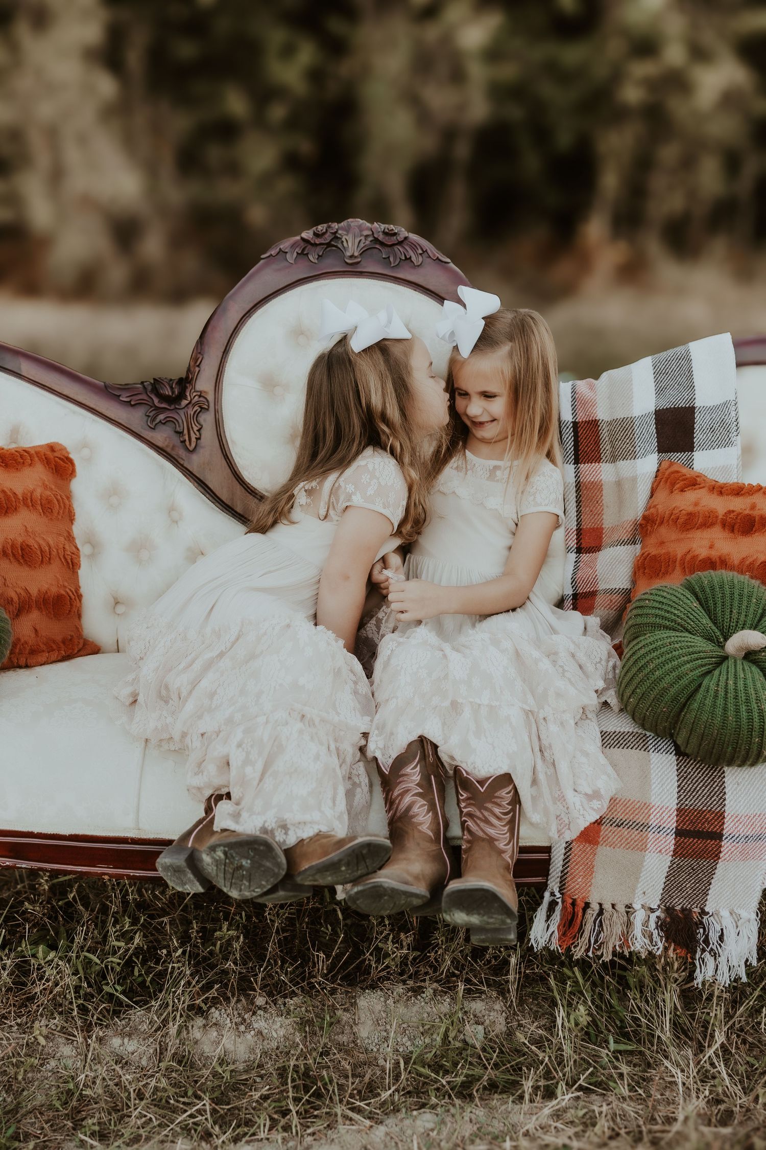 Sweet moment captured on plaid blanket with white dresses and pumpkins.