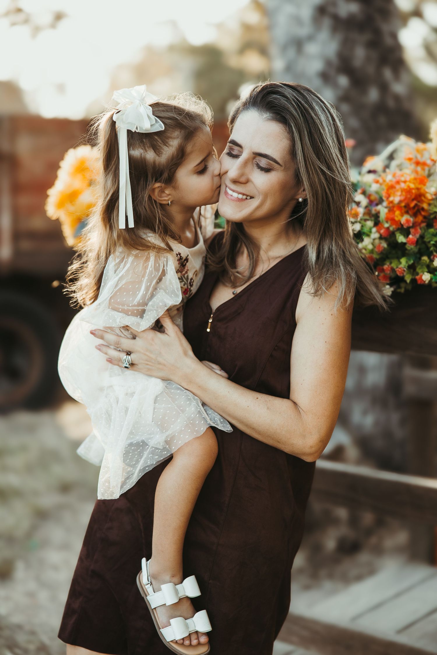 Intimate outdoor portrait session with brown and white outfits against floral backdrop.