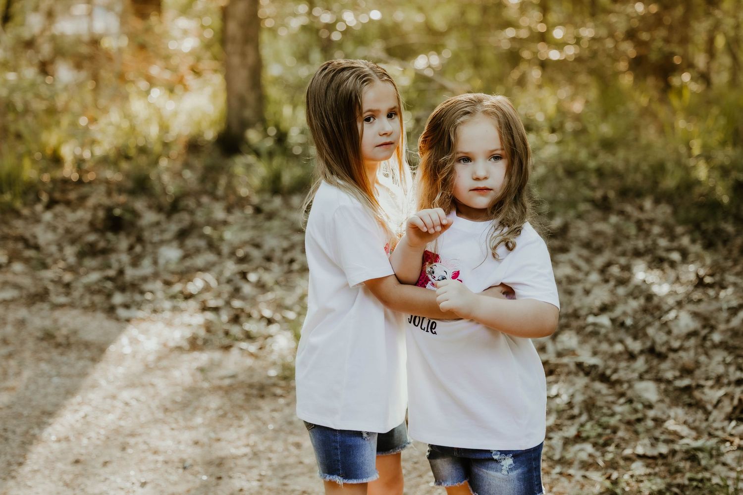 A tender moment is captured between two people in white shirts against a natural backdrop.