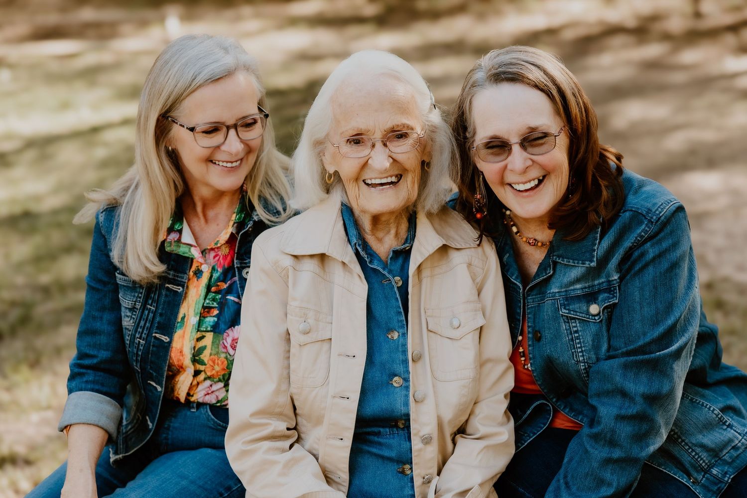 Three generations of family members share joyful moments together while sitting outdoors in casual attire.