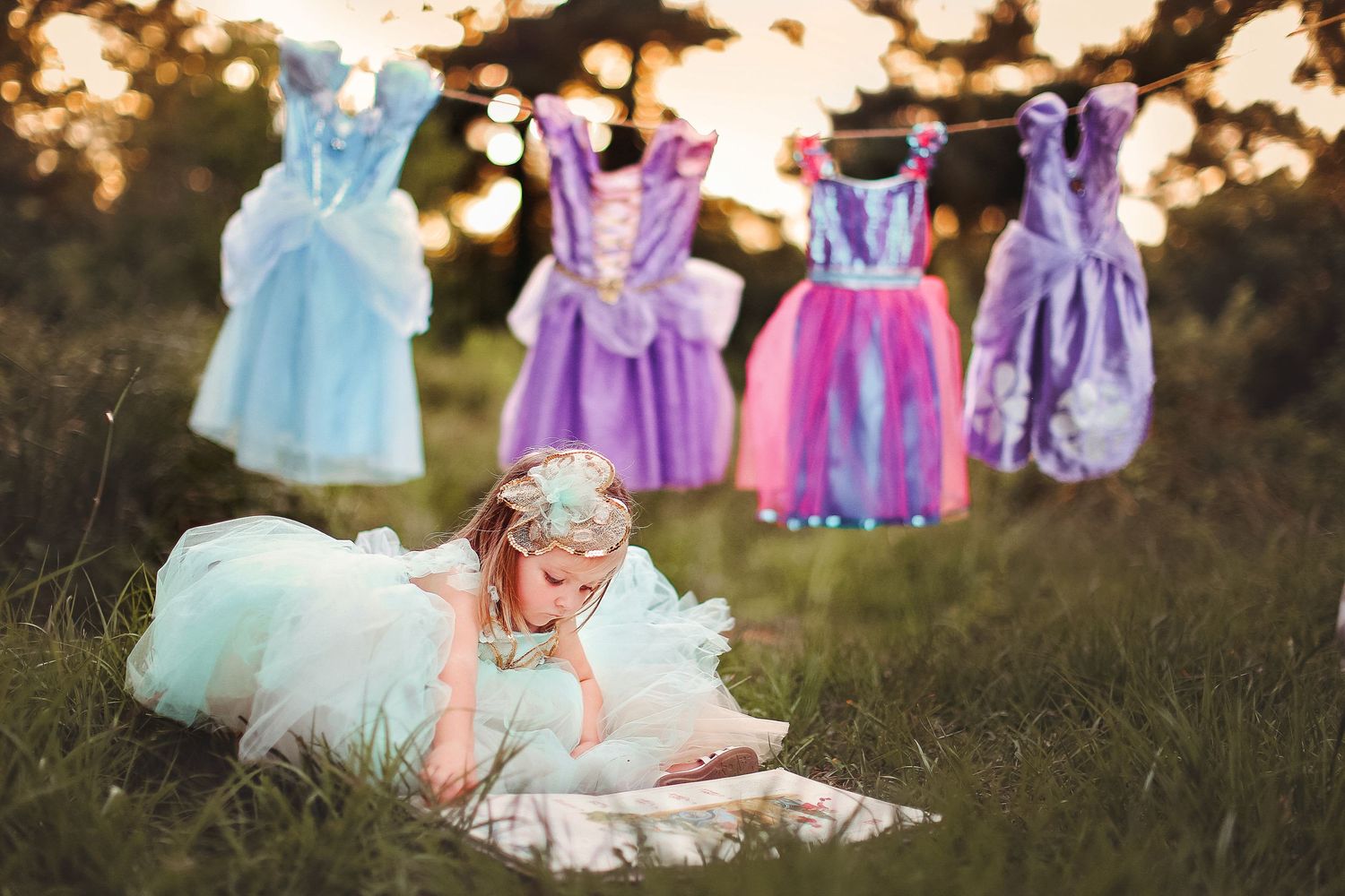 Collection of colorful princess dresses displayed outdoors at sunset.