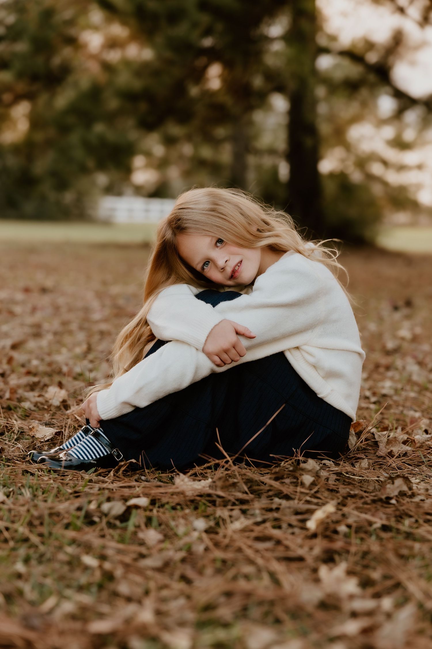 Person in white sweater lying on autumn leaves in a dreamy outdoor portrait series.