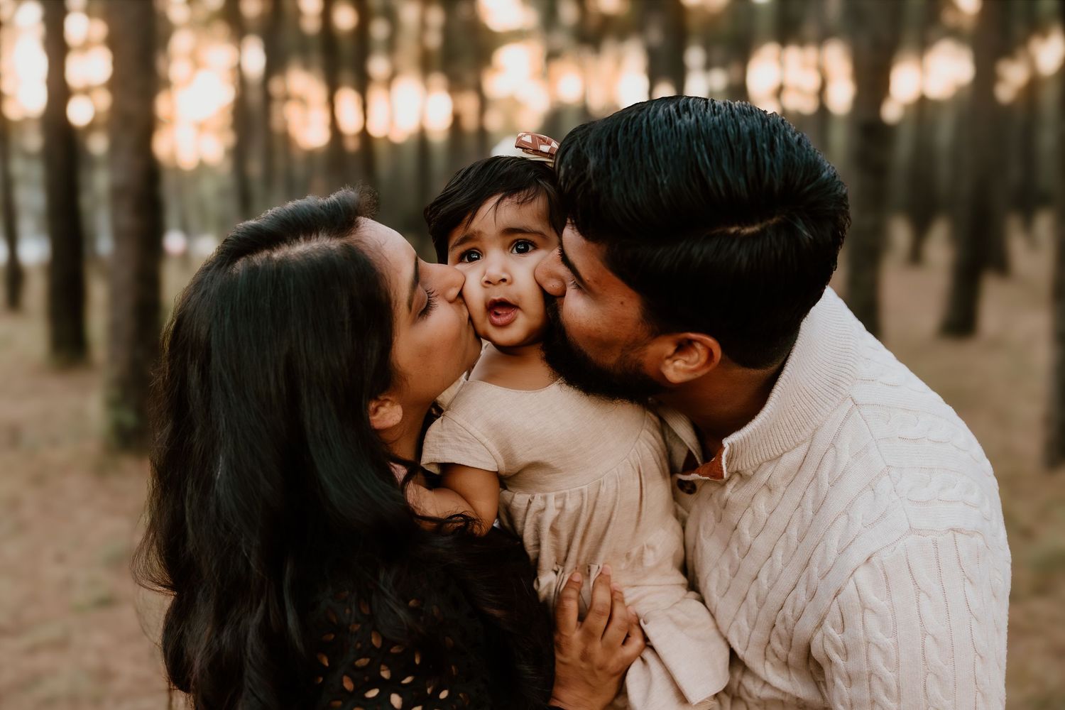 Intimate family moment captured in a warm sunset glow through a forest setting.