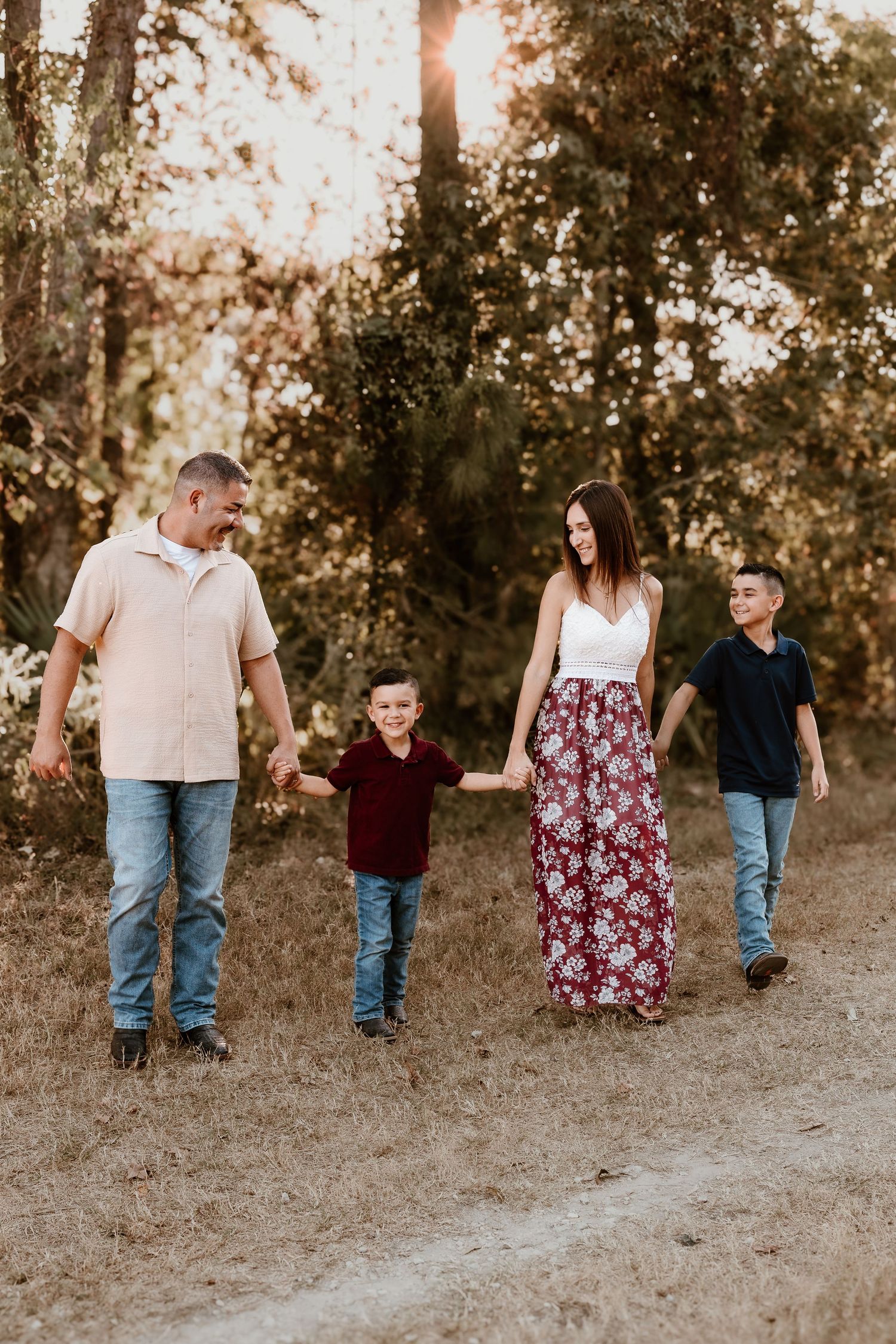 Family walking together on a dirt path during golden hour in casual coordinated outfits.