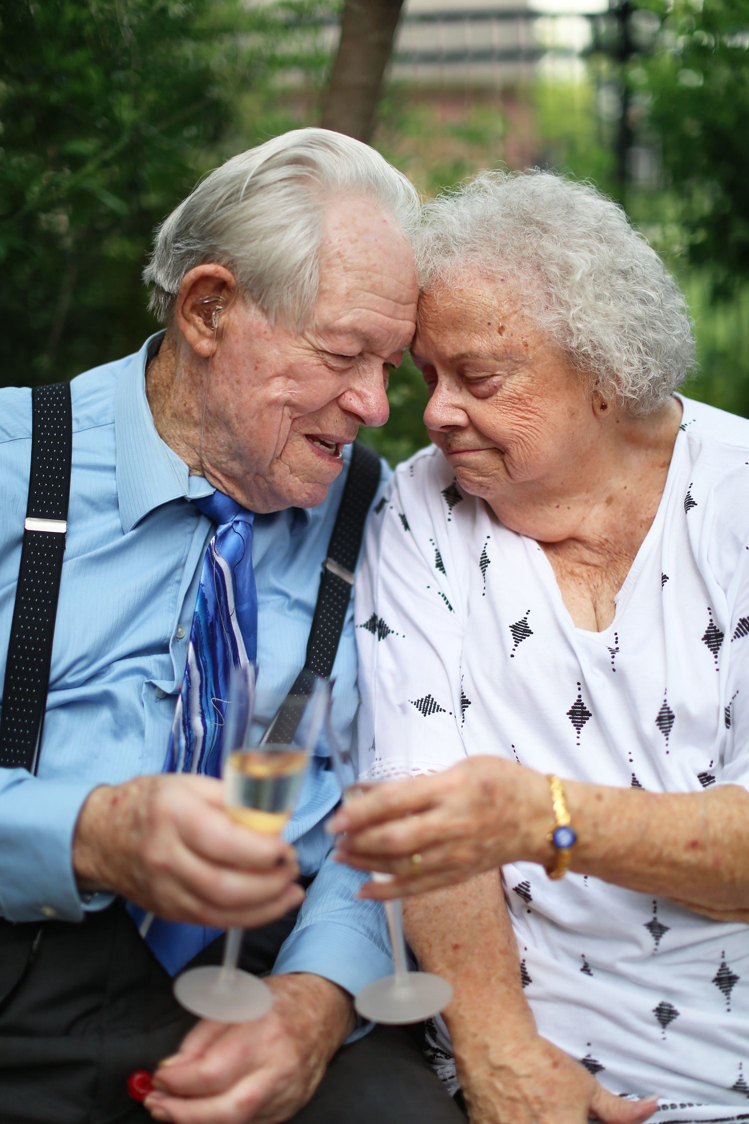 Elderly couple sharing a sweet moment while sitting outdoors.