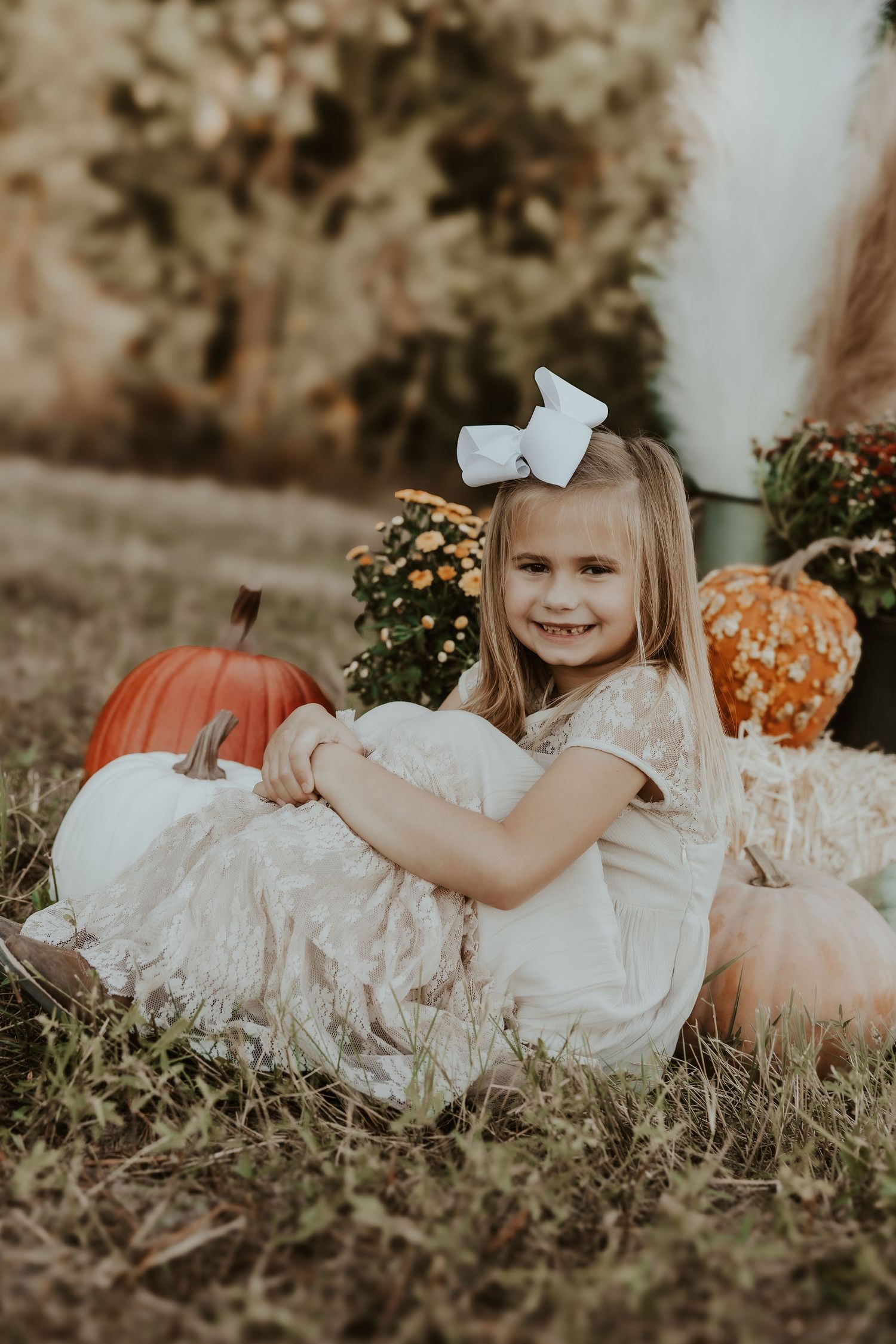 White dress portrait with pumpkins in rustic fall setting.