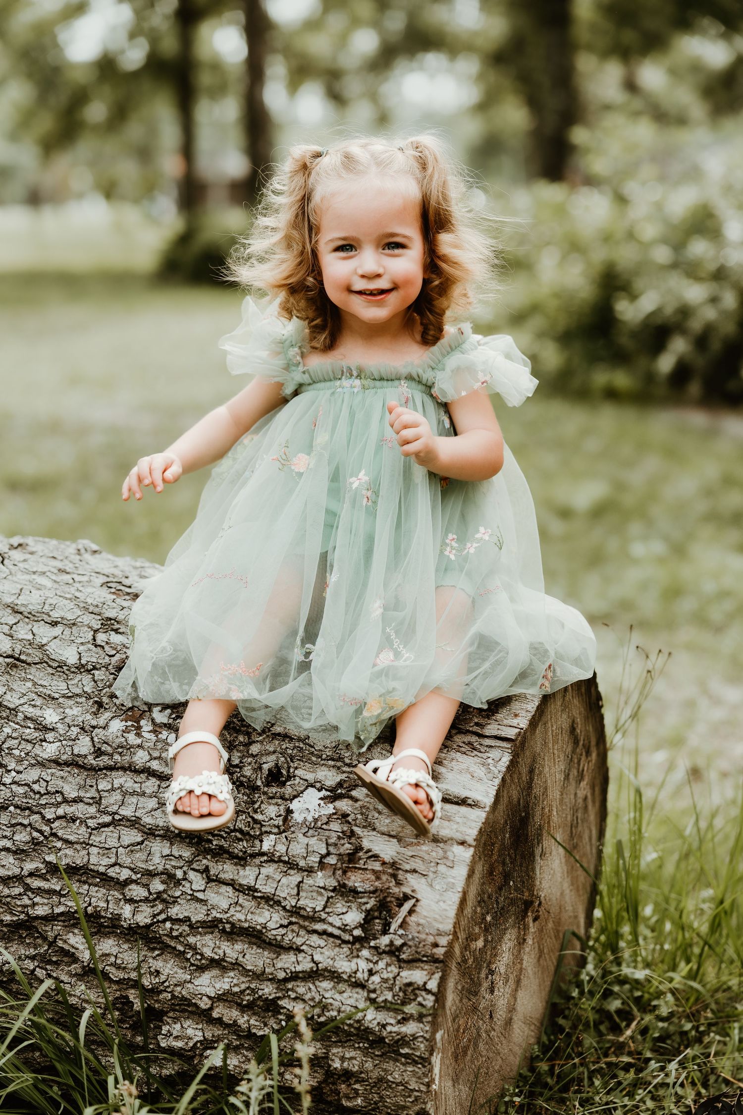 Joyful outdoor photography on a rustic log wearing a mint tulle dress.