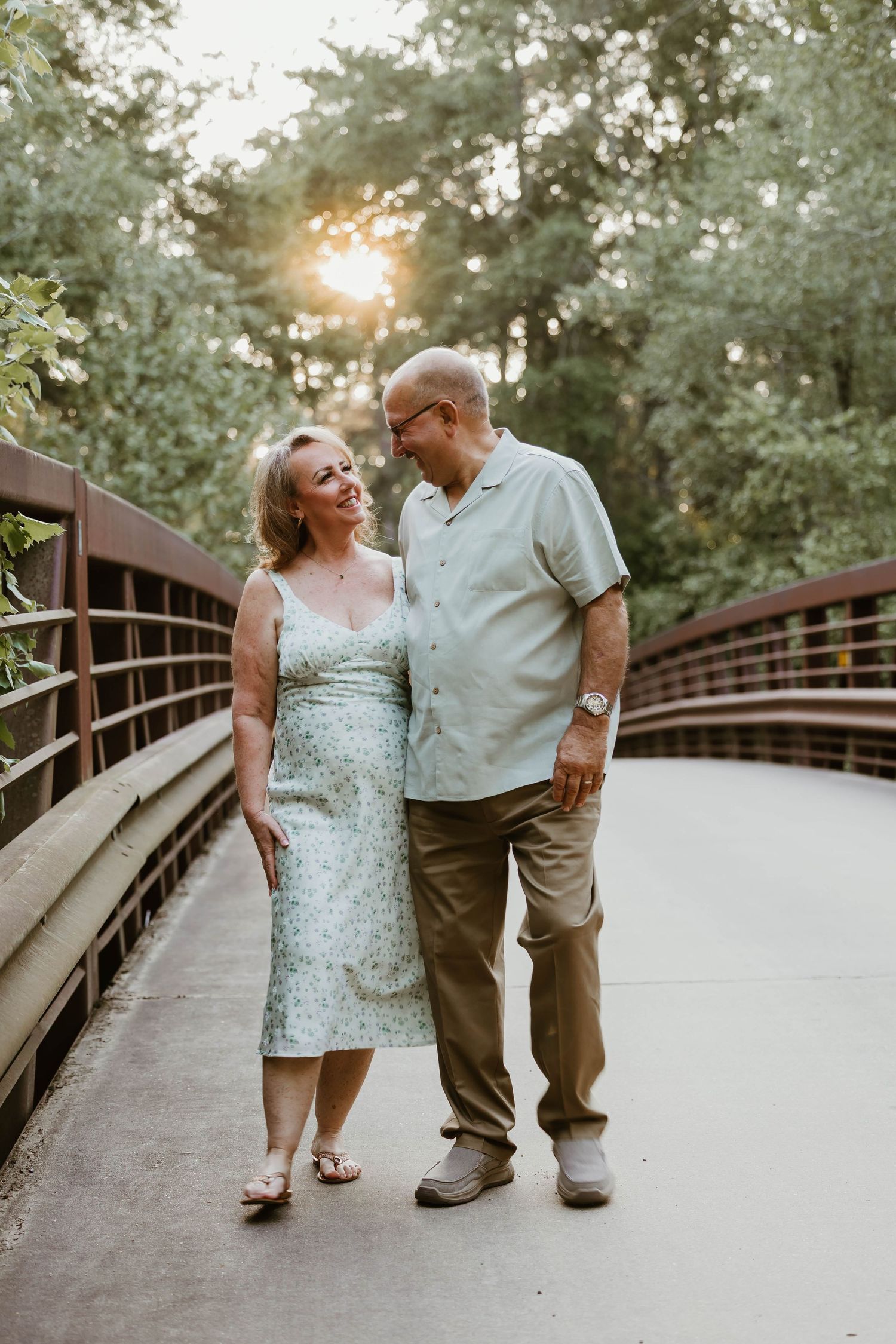 Couple walking together and laughing on wooden bridge path.
