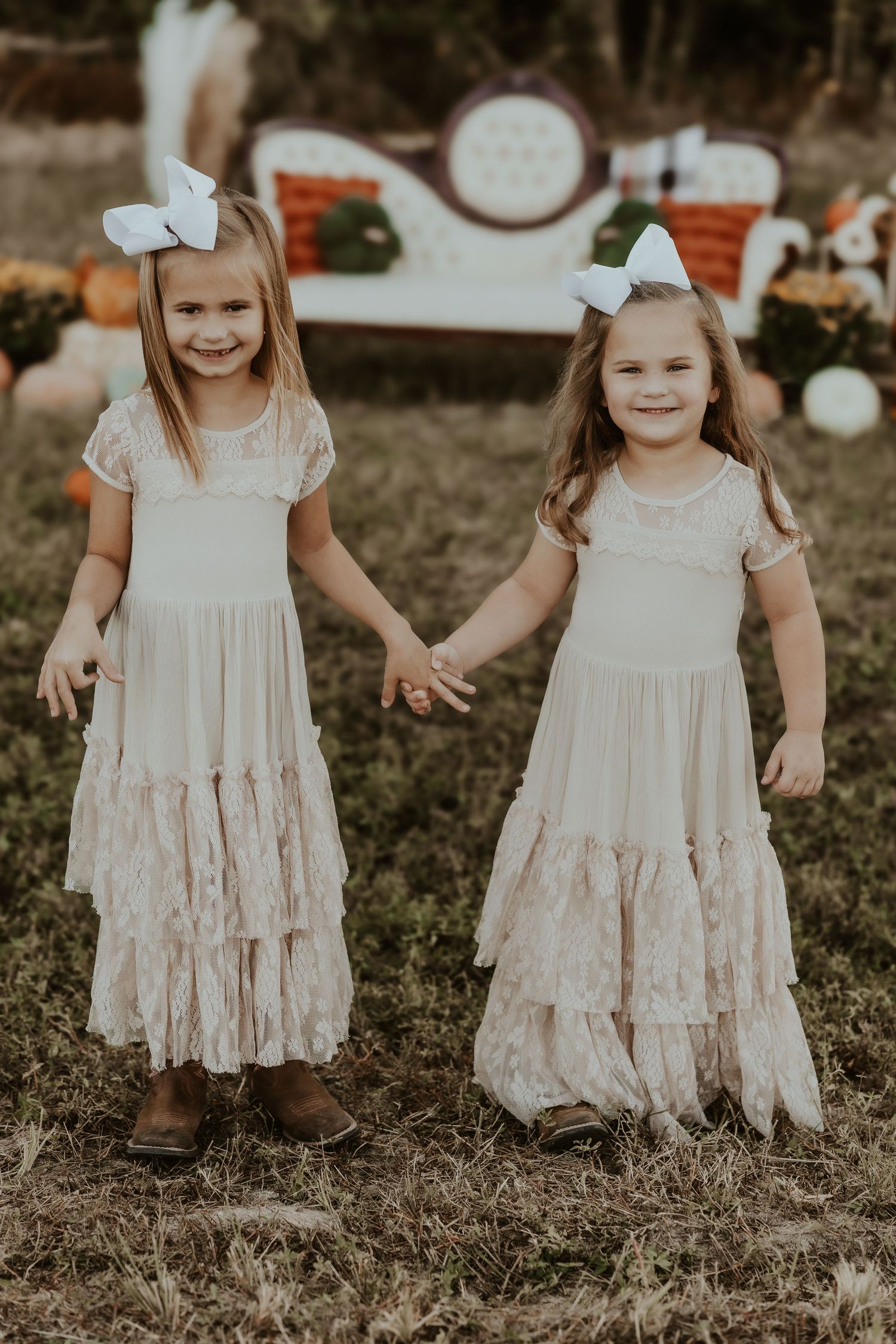 Children in vintage white dresses standing together in autumn setting.