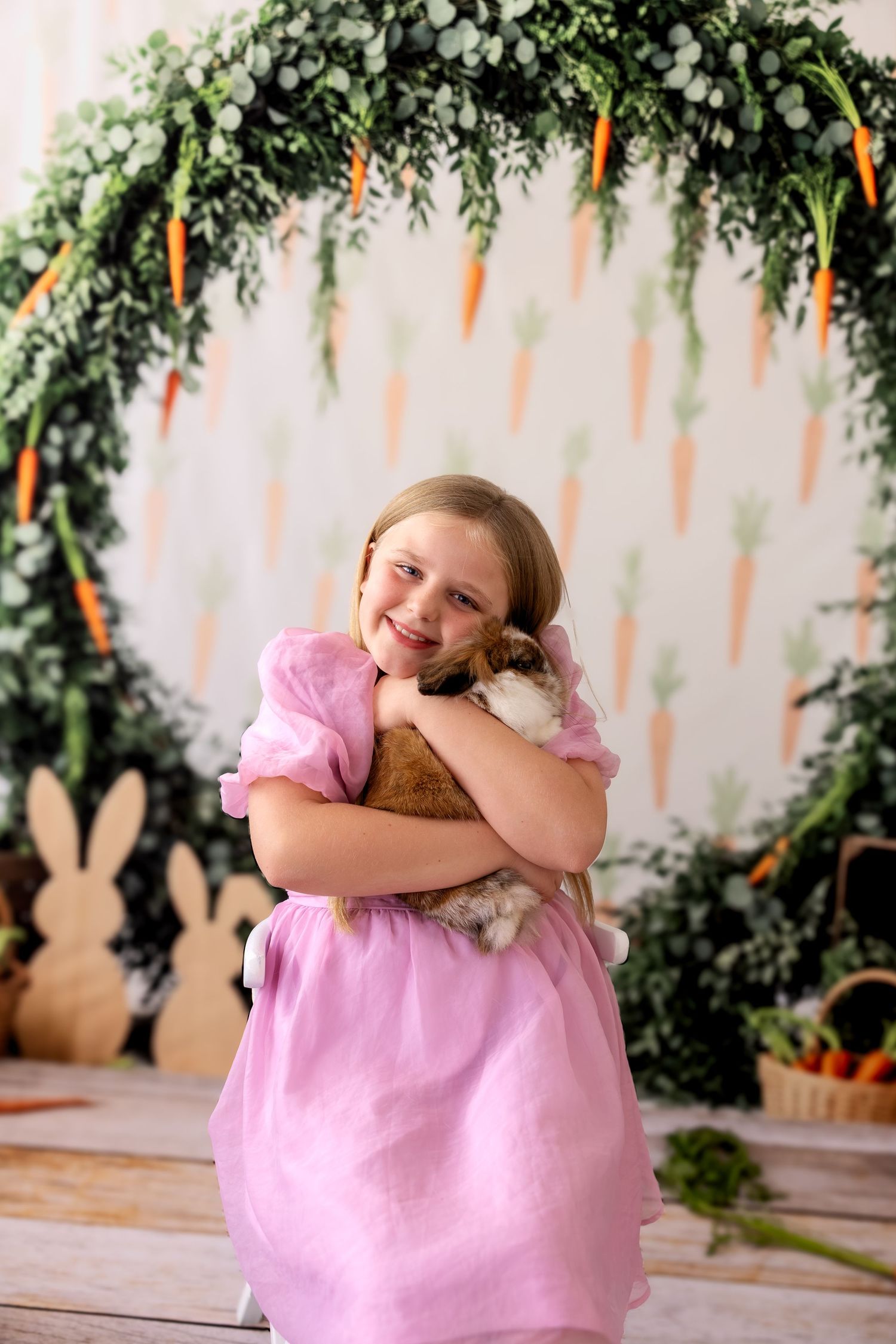 A series of five photos shows someone in a pink dress holding and cuddling with a plush bunny toy against a garden backdrop.