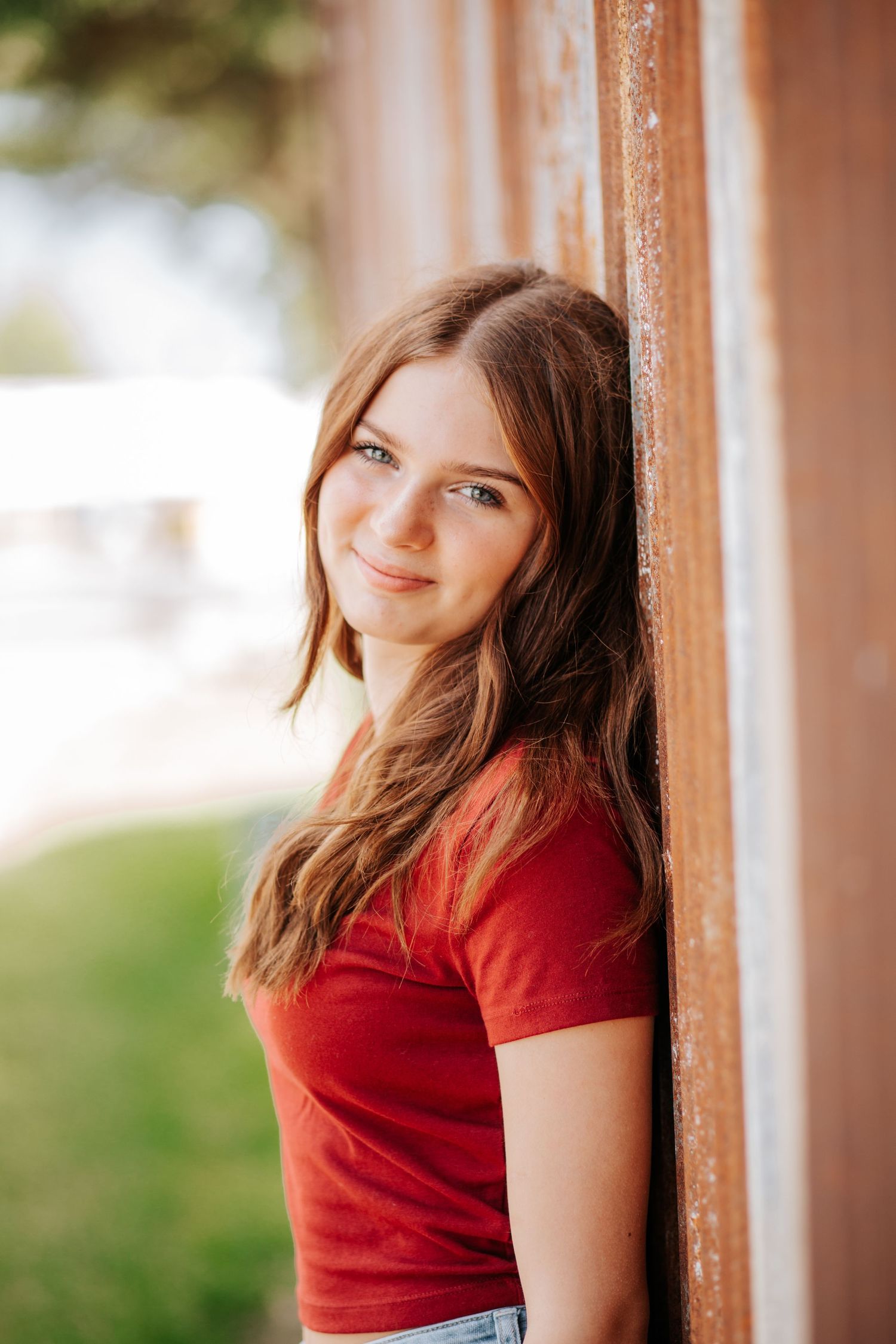 Casual portrait session with red shirt against white columns outdoors.