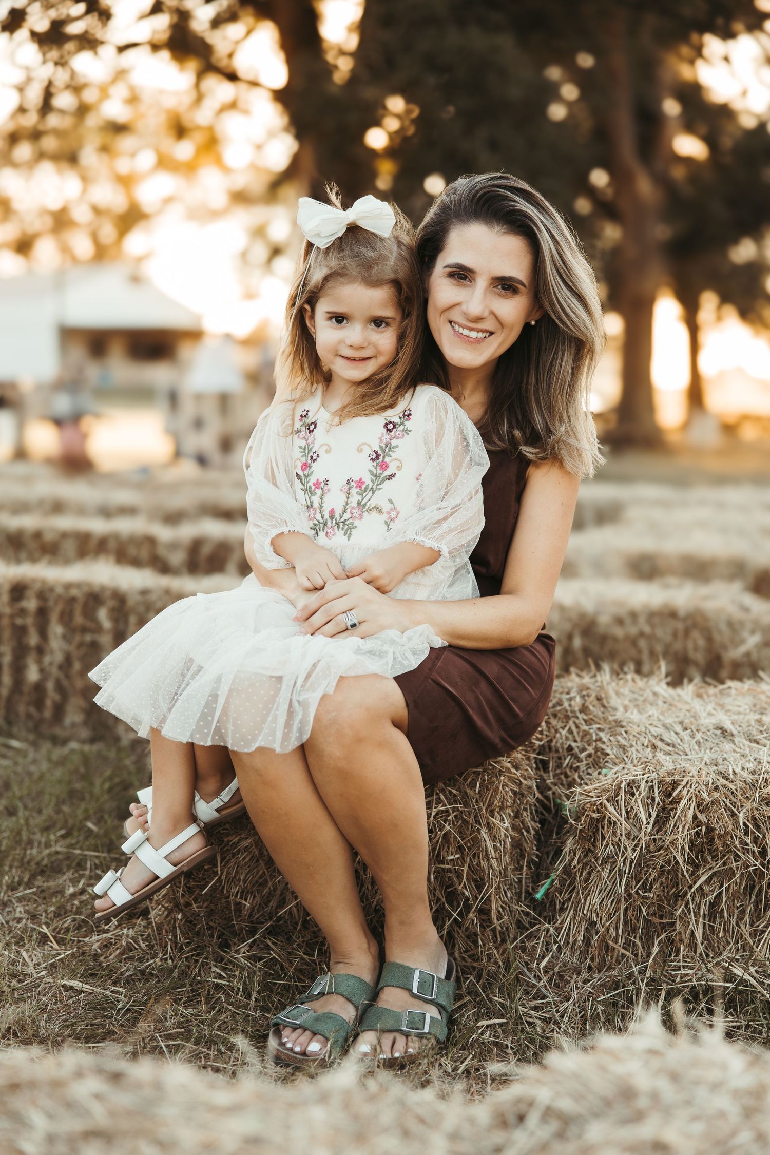 Casual outdoor portrait session on hay bales during golden hour sunset.