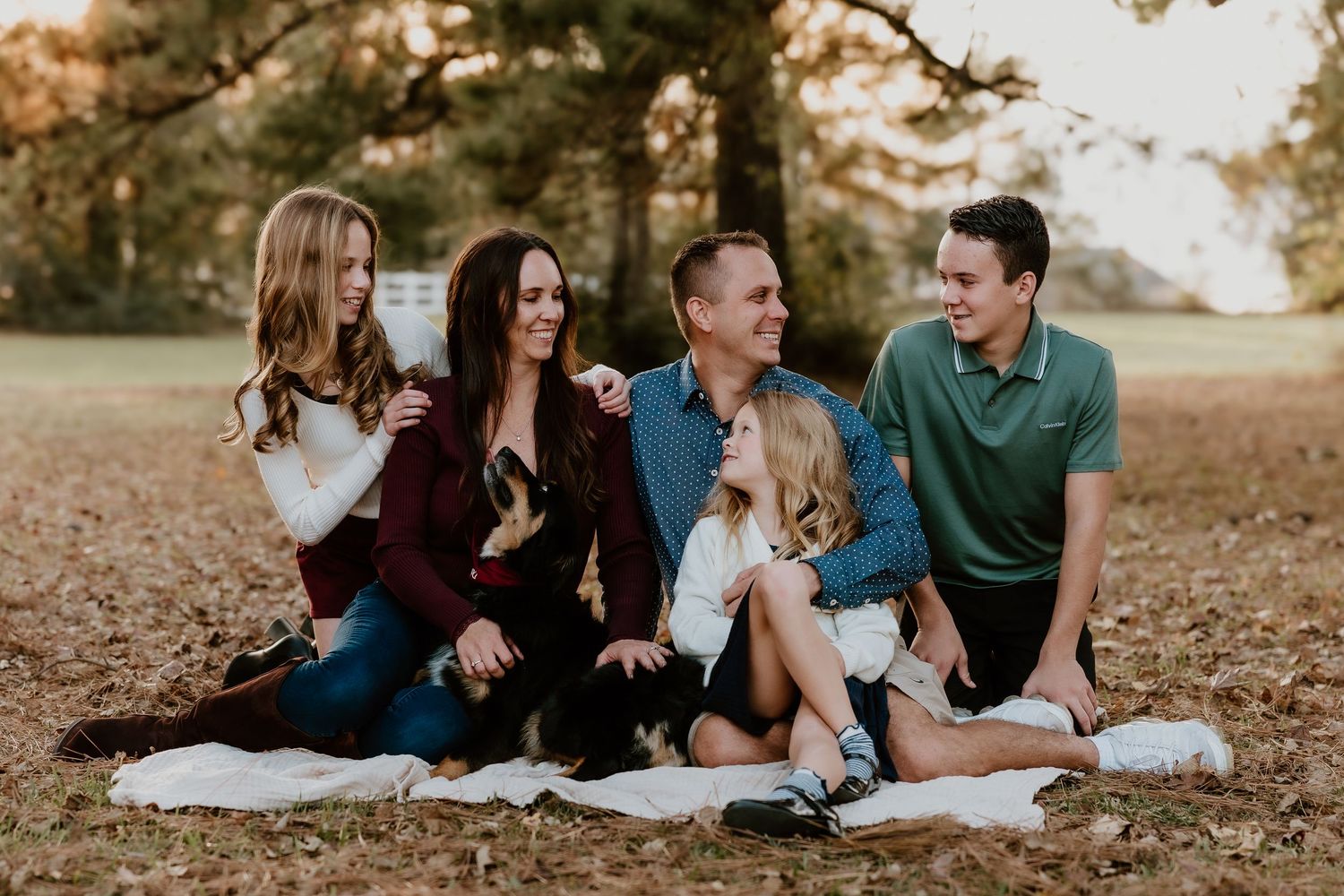 A family lying on a blanket outdoors in autumn, sharing joyful moments together during a photo session.