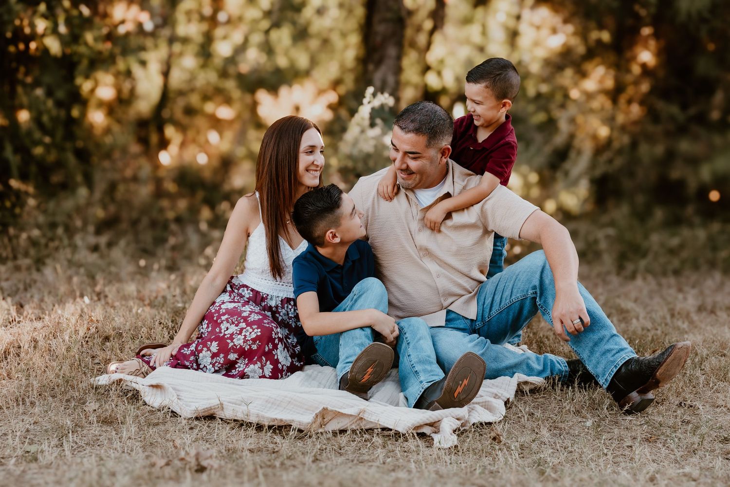 A family relaxes together on a blanket outdoors during a golden autumn afternoon photoshoot.