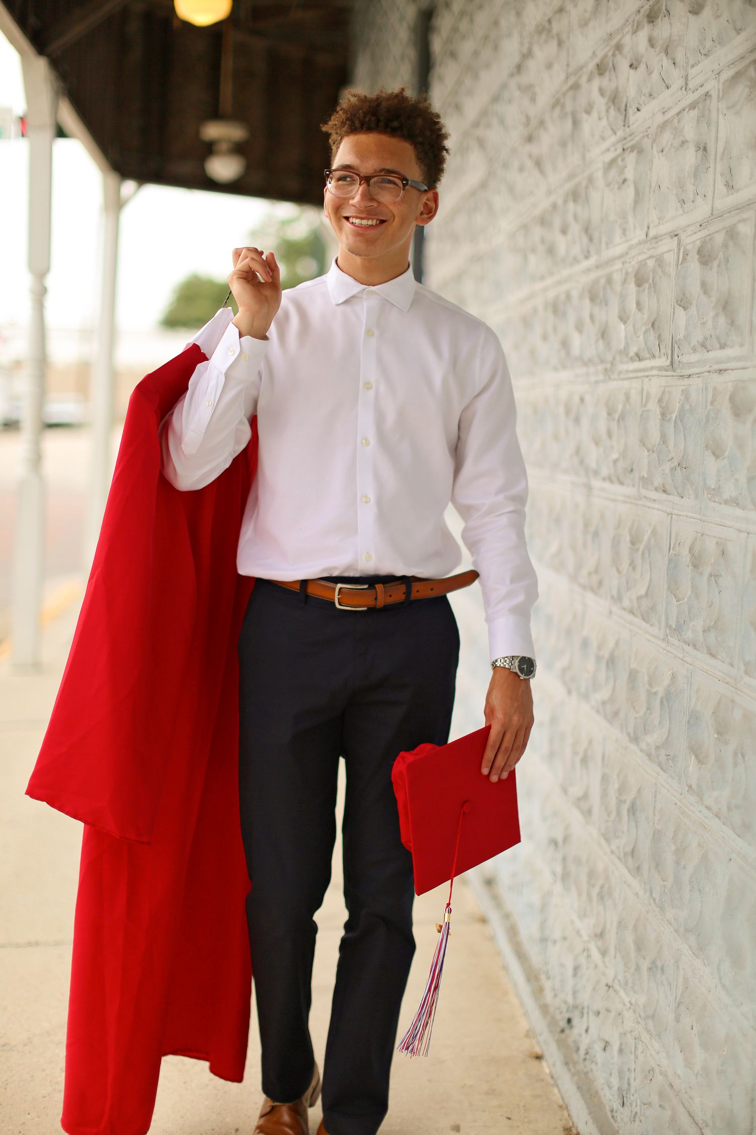 Professional portrait session showing person in white shirt and red jacket walking down a covered walkway.