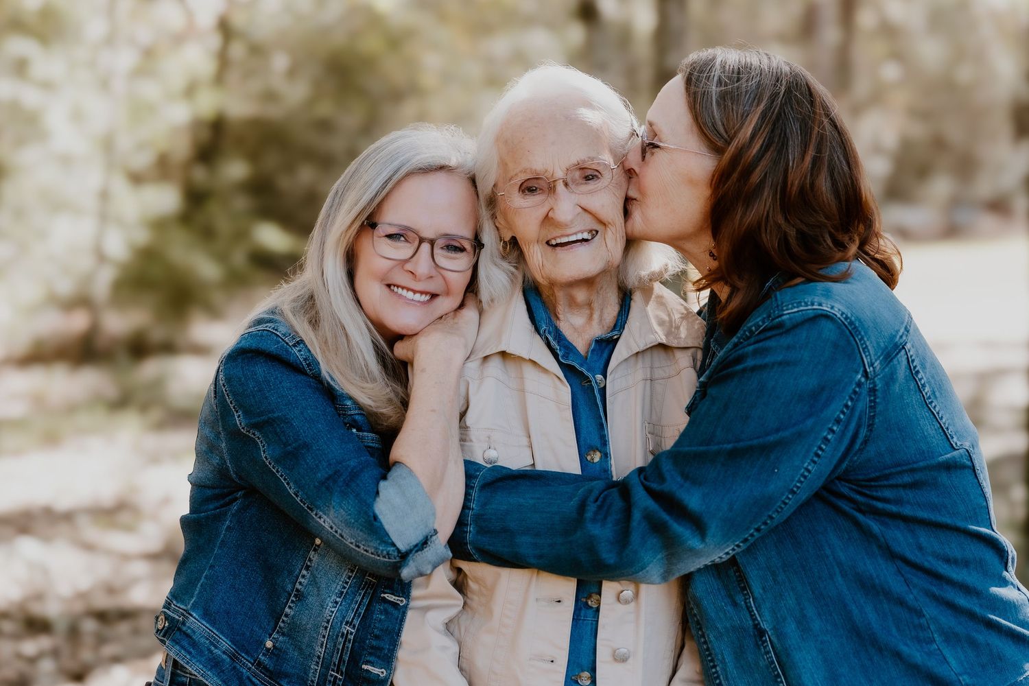 A group wearing coordinating denim and white outfits smile together during an outdoor photo session.