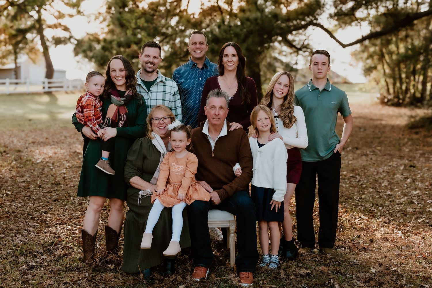 A group of people in coordinated outfits pose together outdoors during a fall photography session.