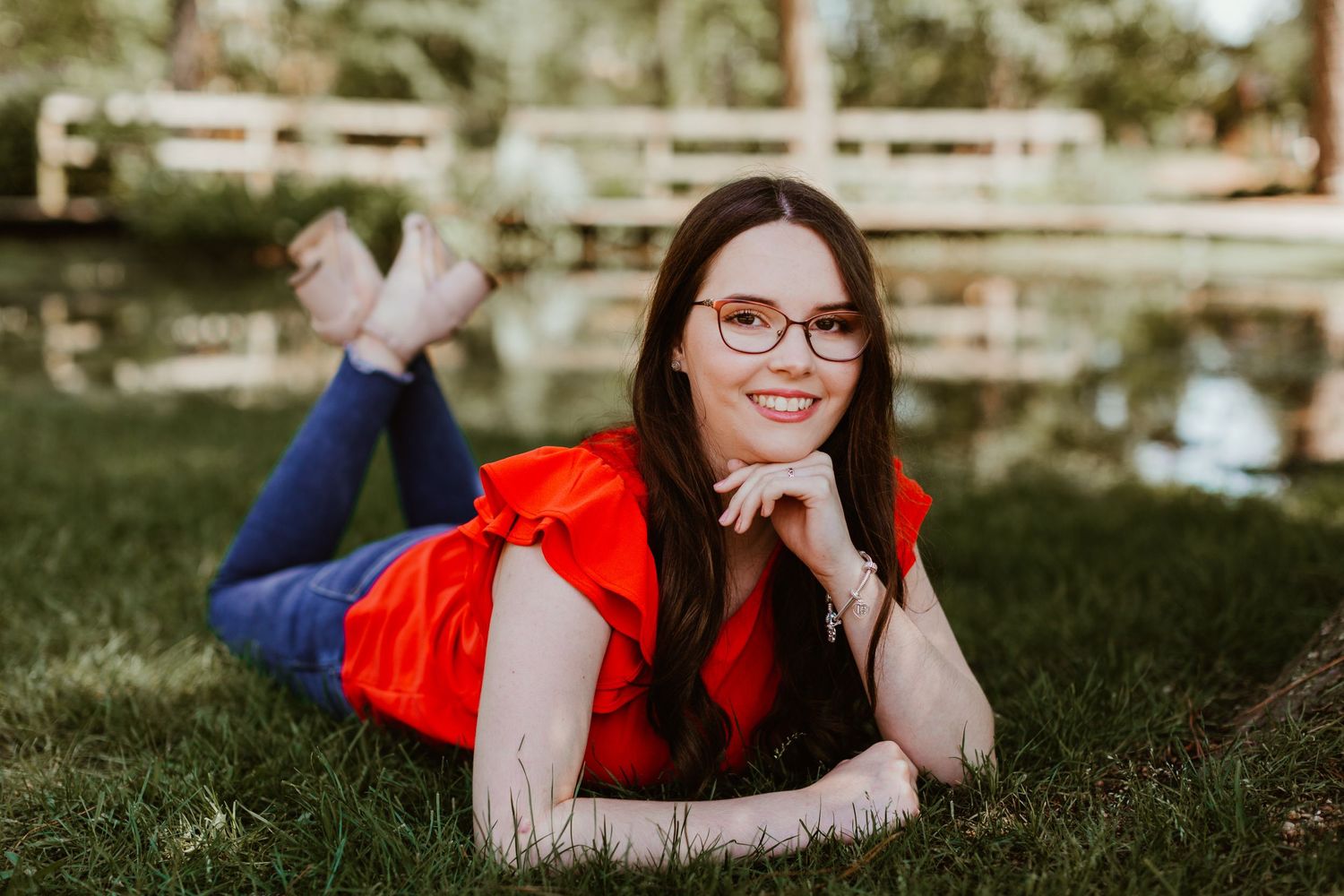 Woman in red top relaxing on grass in casual outdoor portrait.