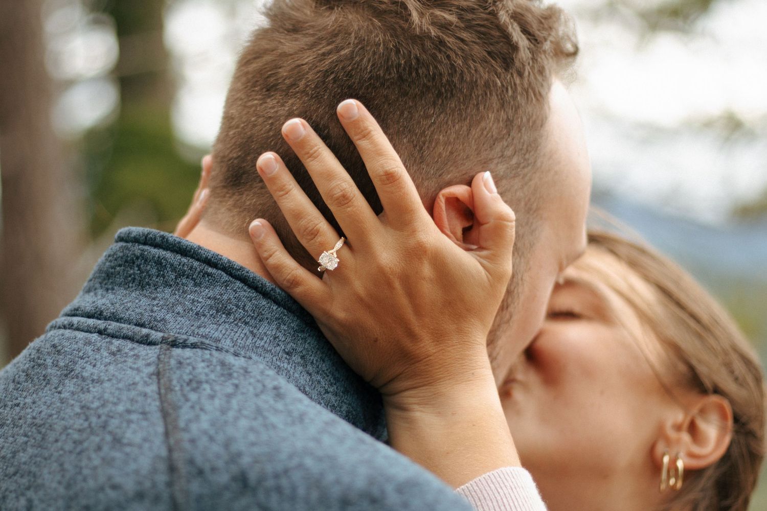 Close up shot of an engagement ring displayed during an intimate moment outdoors.