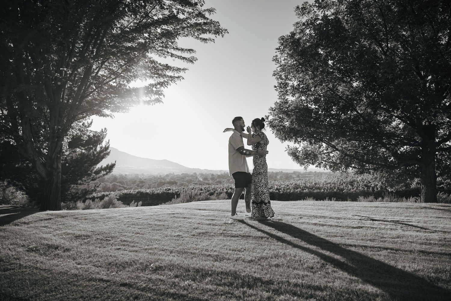 A silhouetted figure walks along a scenic hilltop path at sunset casting long shadows across the grassy landscape.