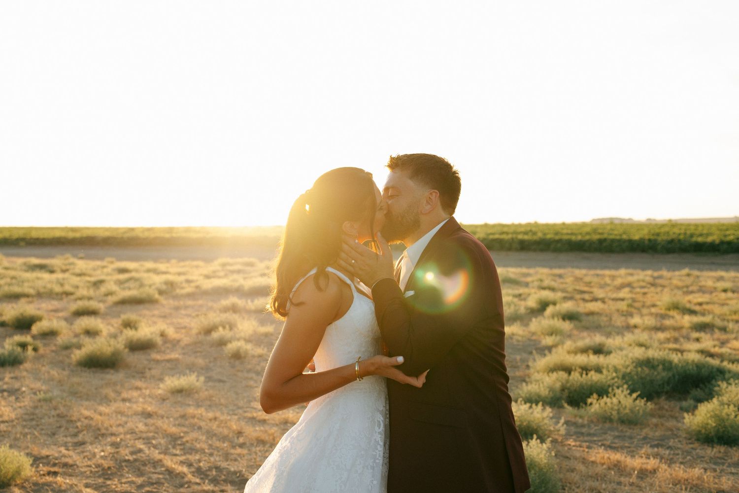A romantic sunset silhouette of newlyweds sharing an intimate moment in a golden desert landscape.