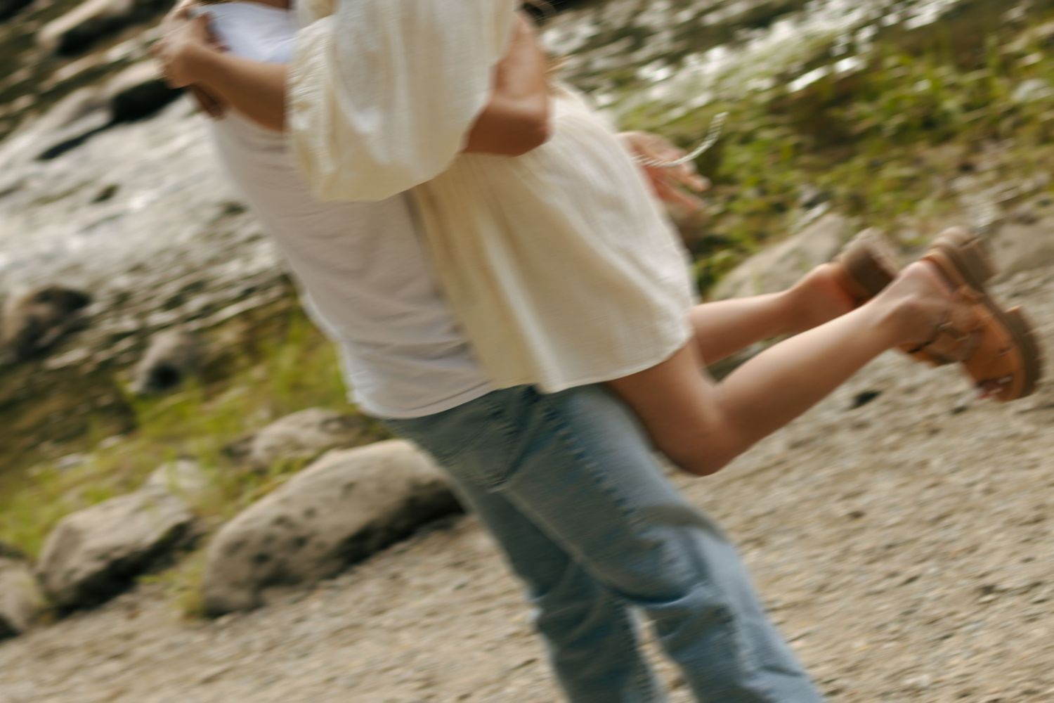 Couple embracing and spinning outdoors on rocky terrain, motion blur capturing a romantic and playful moment.
