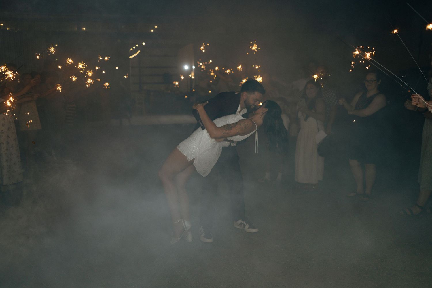 A sparkler-lit wedding celebration with guests creating a magical tunnel of light for the newlyweds.