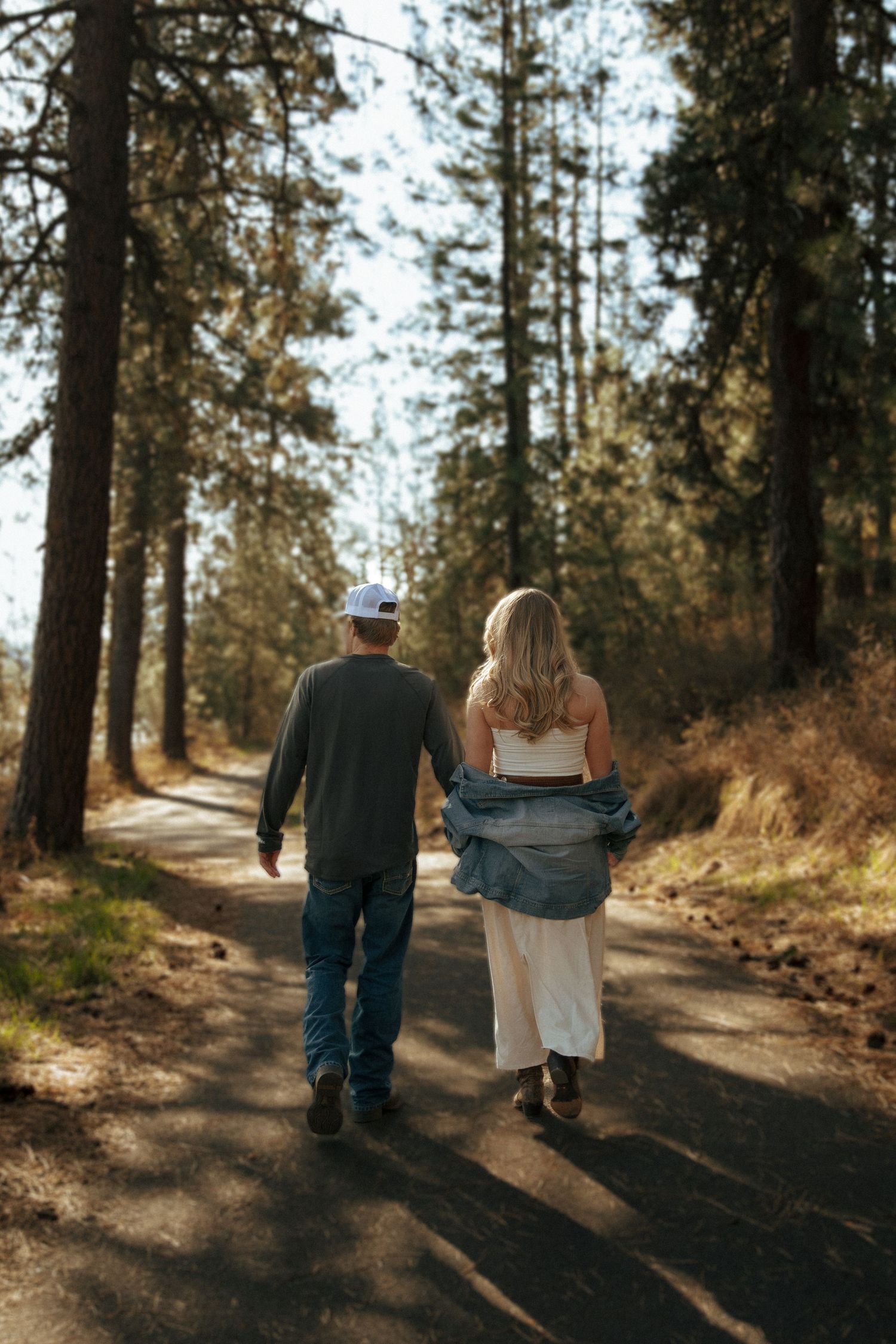 A couple walks hand in hand down a peaceful forest trail on a sunny autumn afternoon.