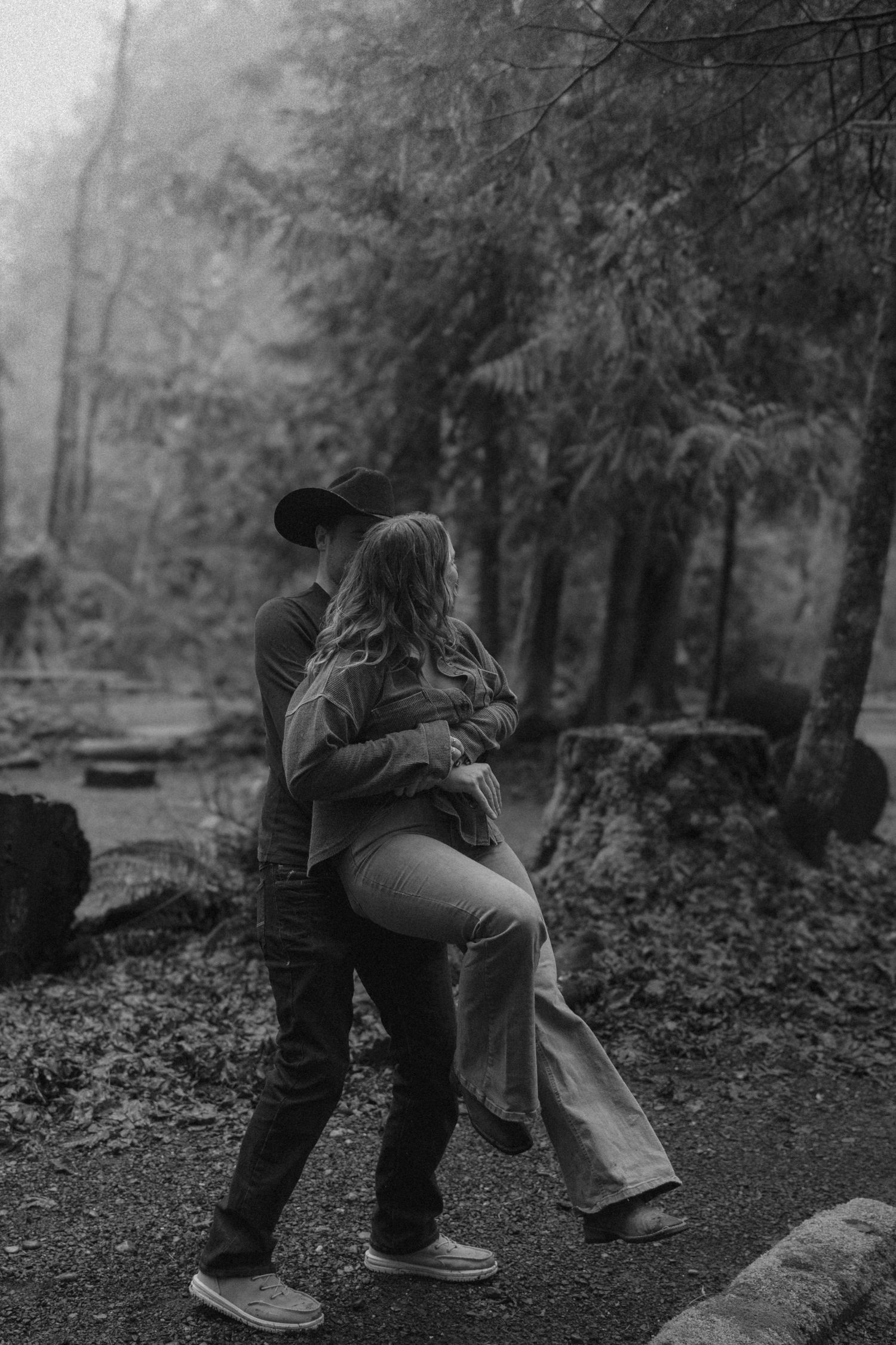 A couple embraces in a moody black and white forest setting, captured in sequential photographs showing intimacy.