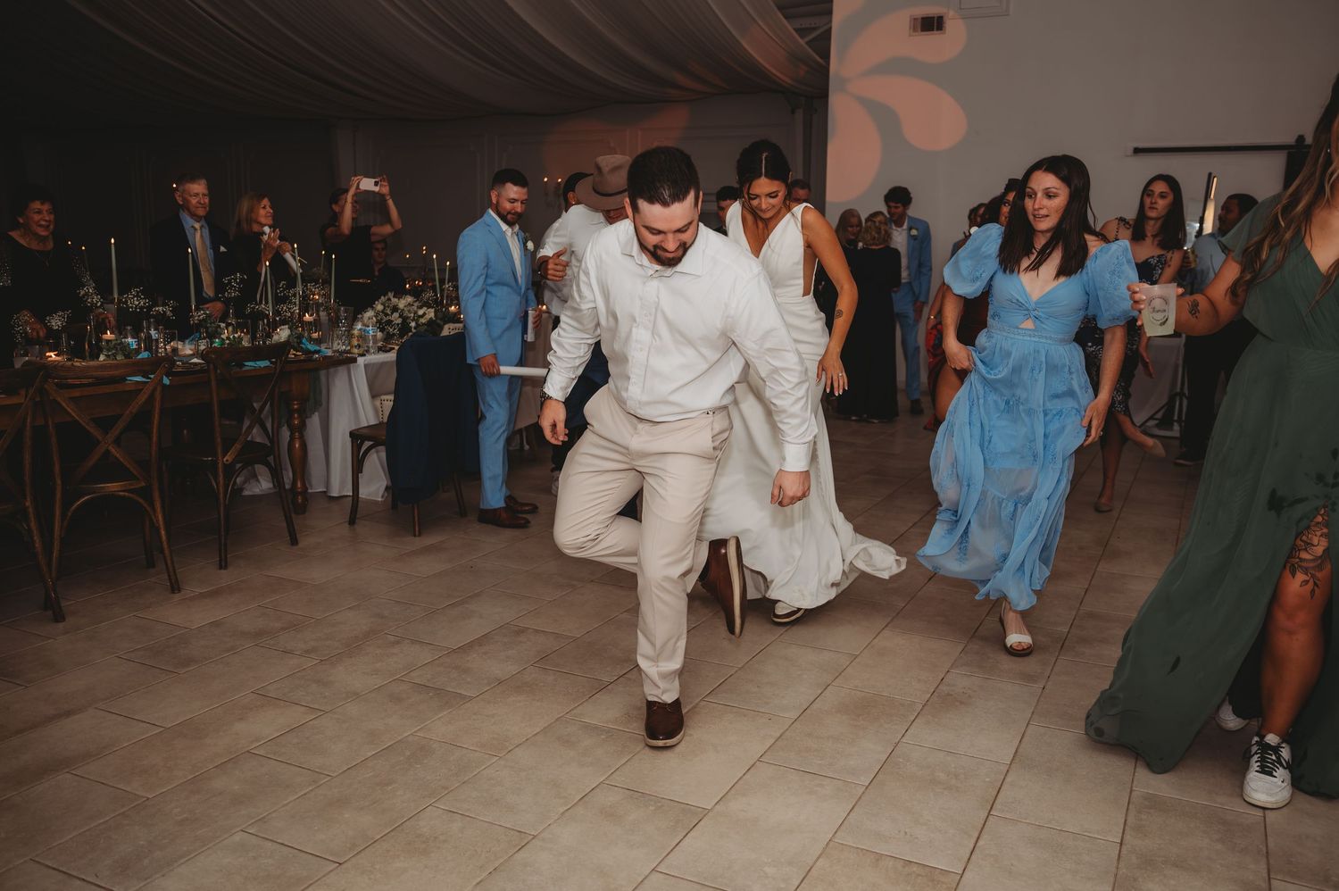 People dancing and celebrating at a lively wedding reception on a dance floor in an indoor venue during a Panama City Beach wedding.