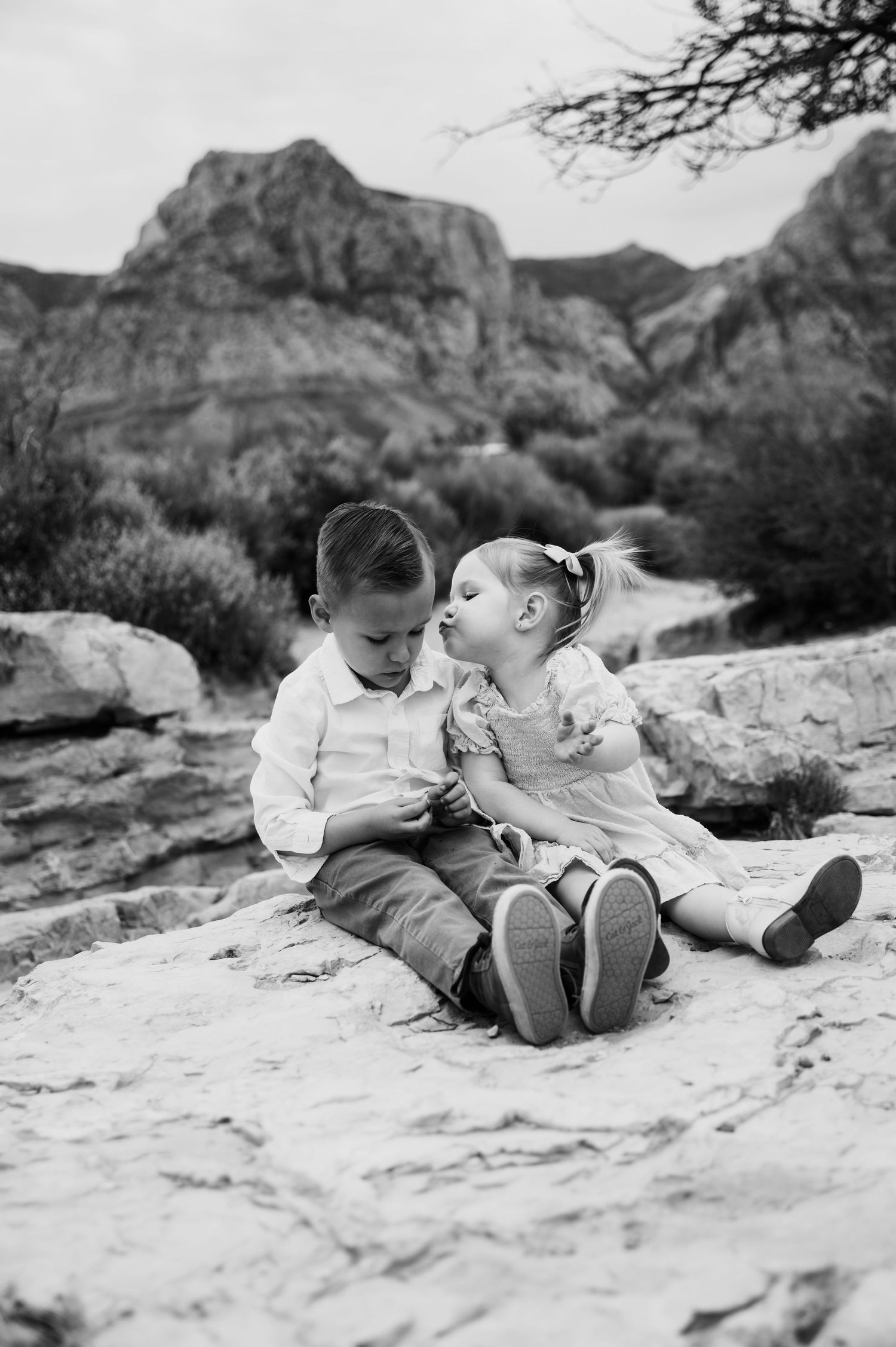 Little girl kissing her brother’s cheek while sitting on the ground during a sibling Panama City Beach photo session.