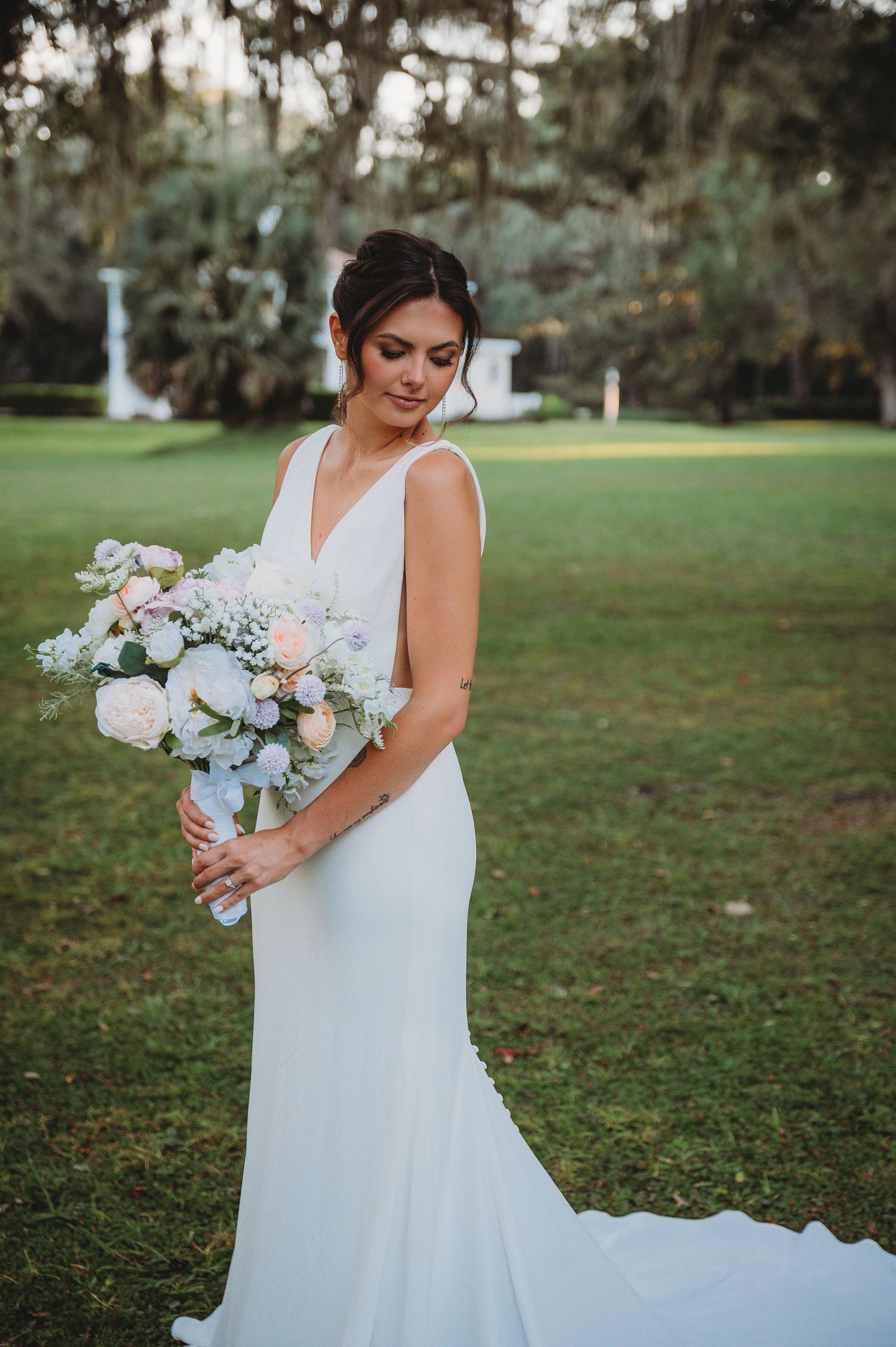 Bride in flowing white gown holds romantic pastel bouquet of roses and eucalyptus during a Panama City Beach wedding.
